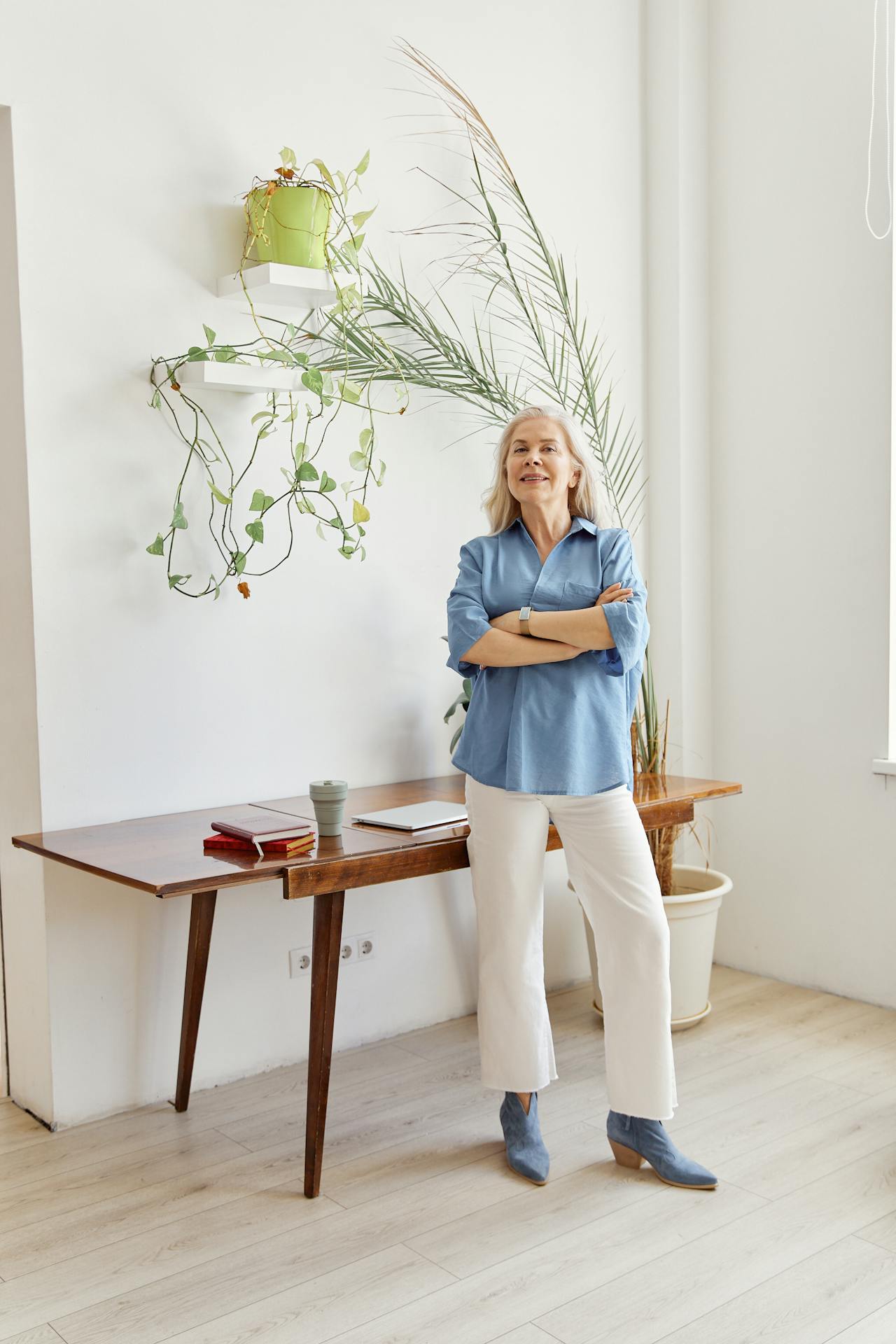 Una mujer mayor feliz de pie en una habitación con los brazos cruzados | Fuente: Pexels