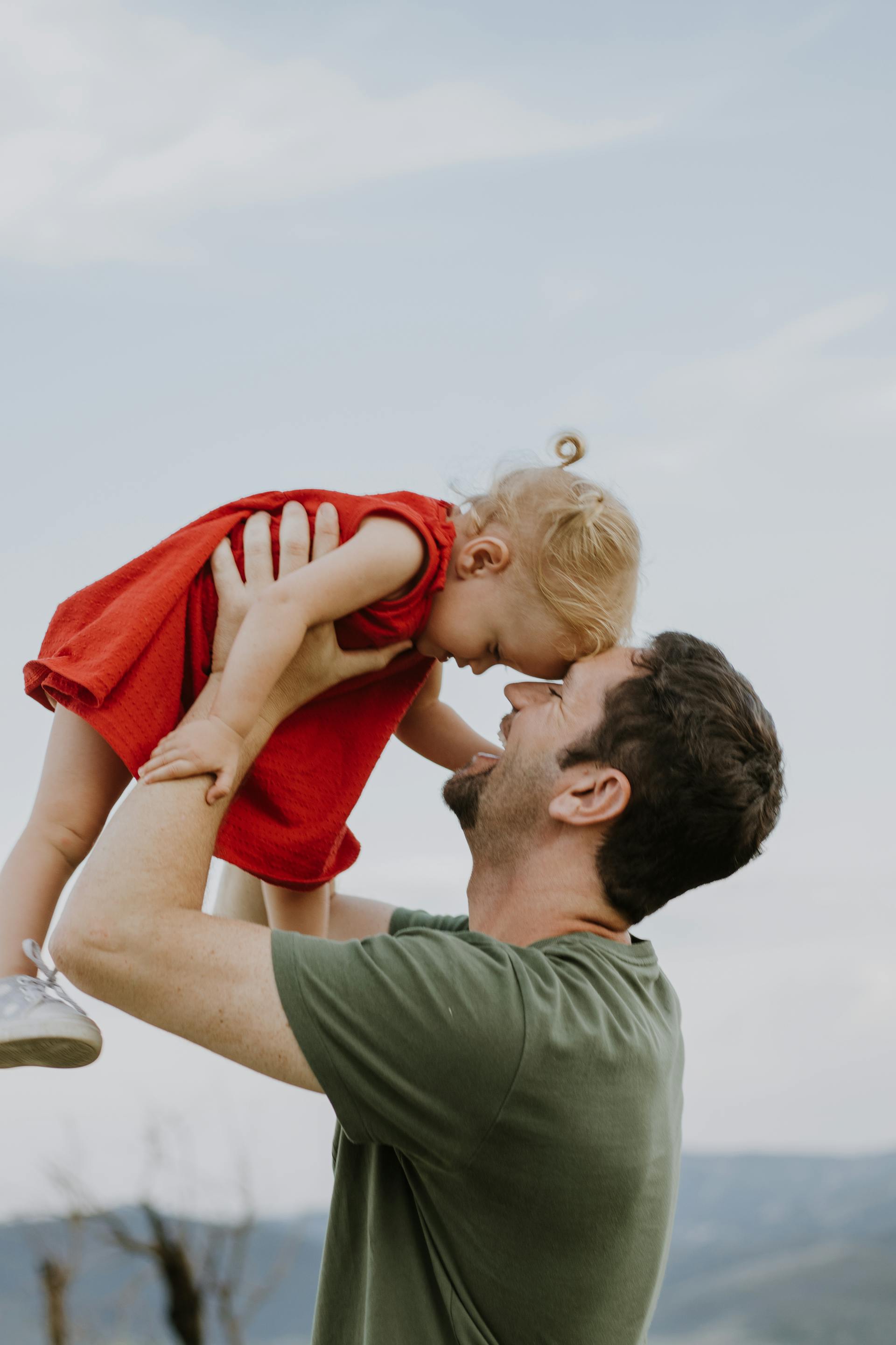 Un hombre feliz con una niña en brazos | Fuente: Pexels
