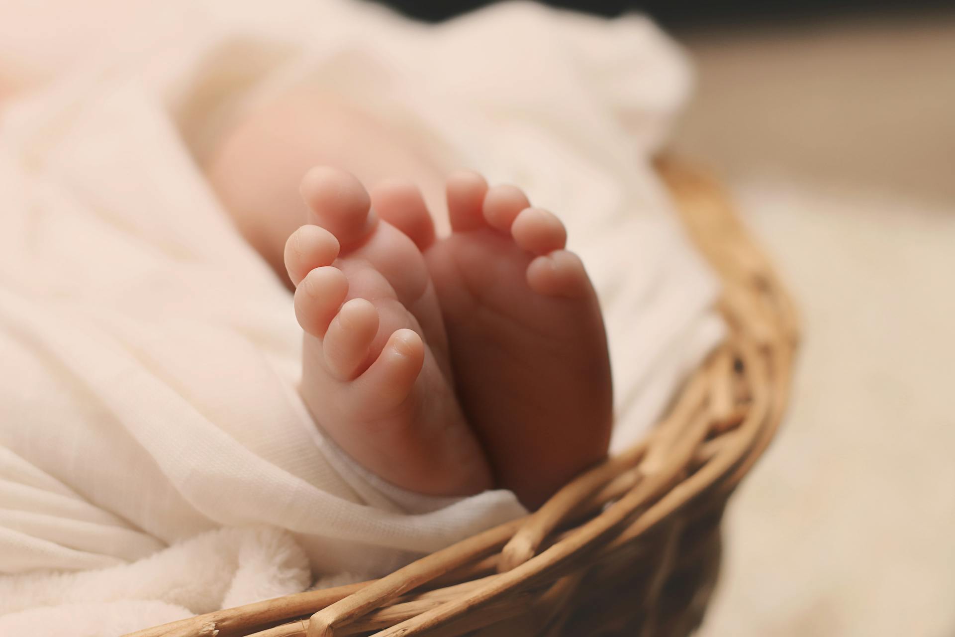 Primer plano de los pies de un bebé sobre una cesta de mimbre | Fuente: Pexels