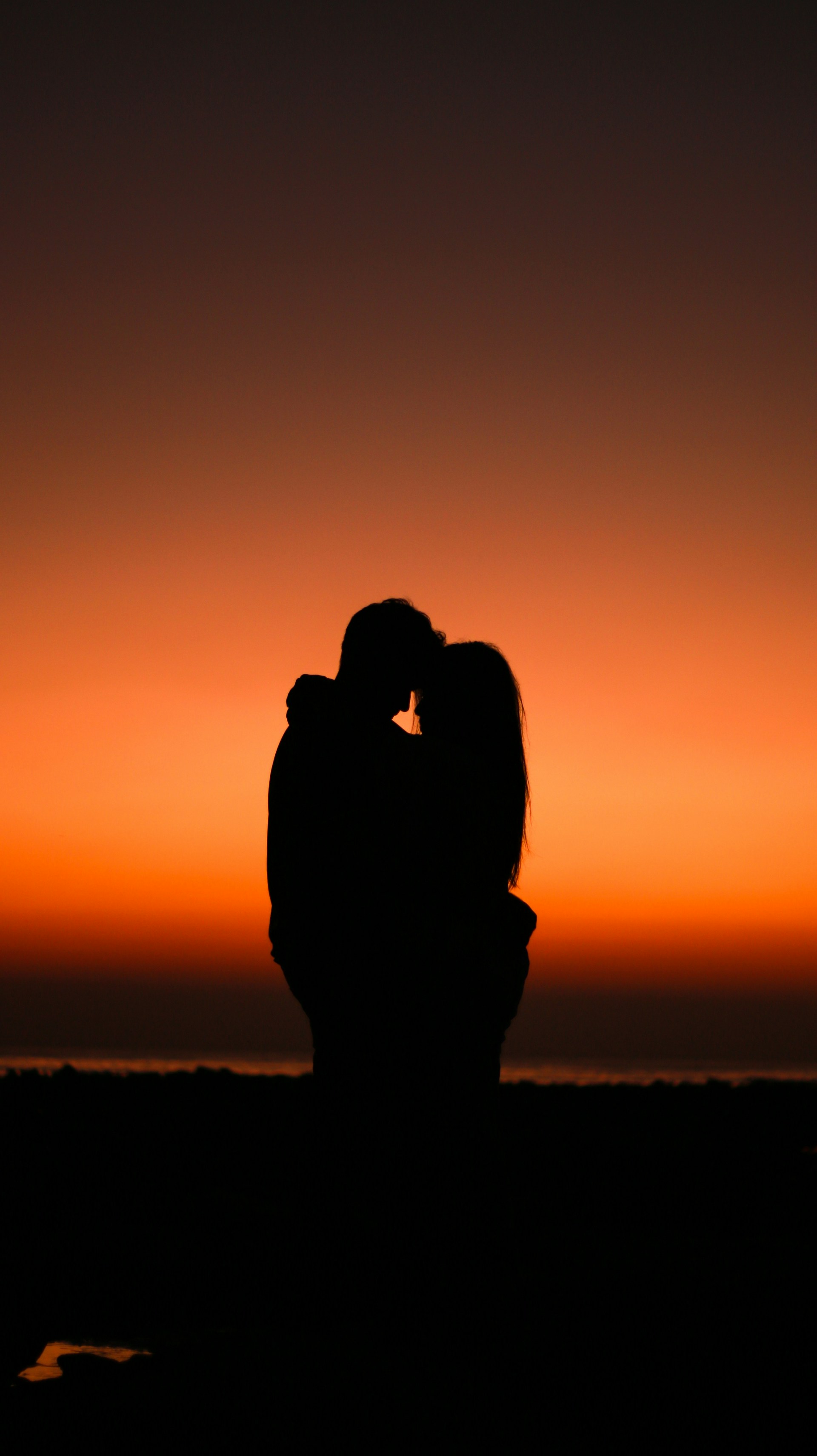 Silueta de una pareja abrazándose en un atardecer dorado | Fuente: Unsplash