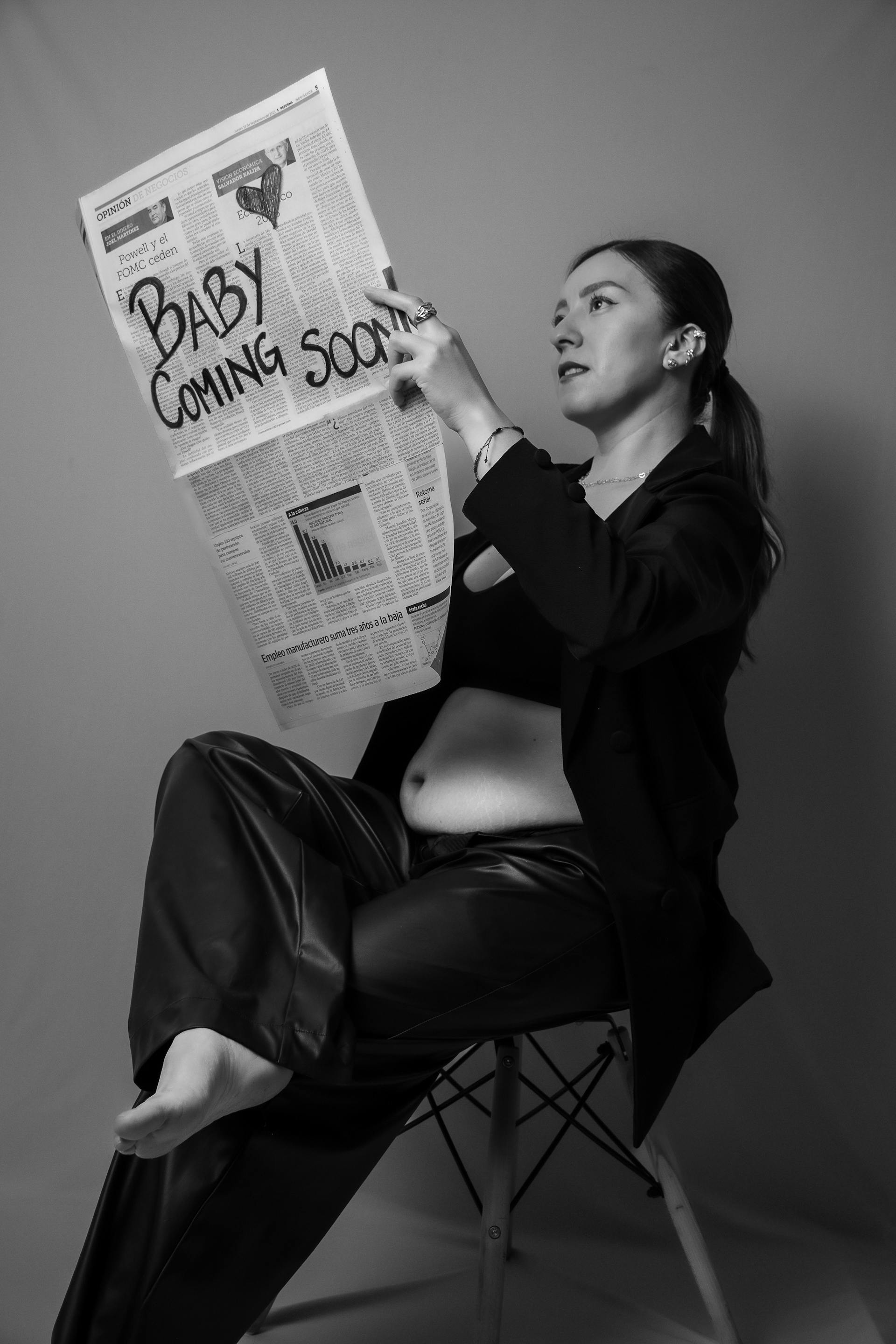 Foto en escala de grises de una mujer embarazada sujetando un periódico | Fuente: Pexels