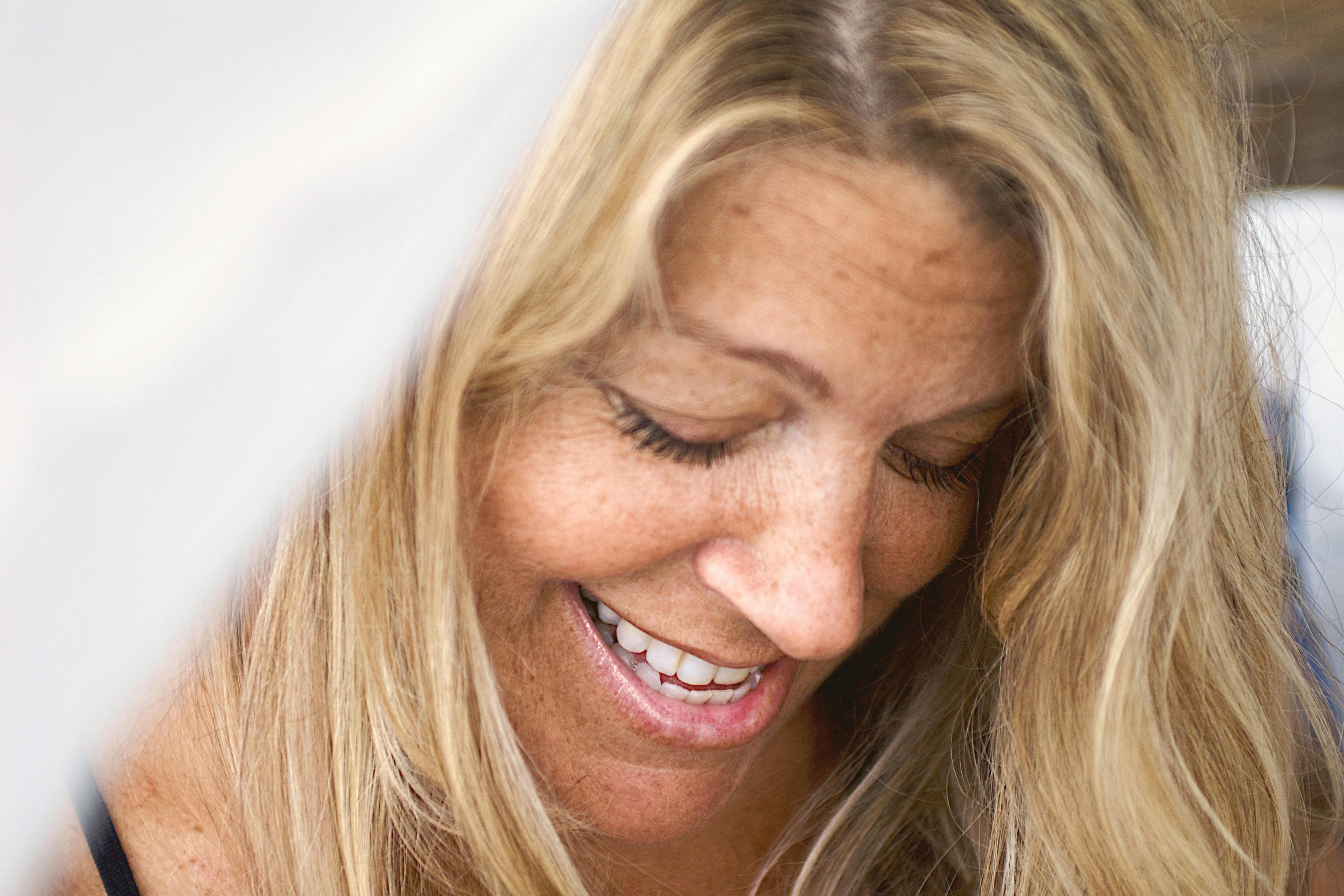 Una mujer feliz mirando hacia abajo | Fuente: Pexels