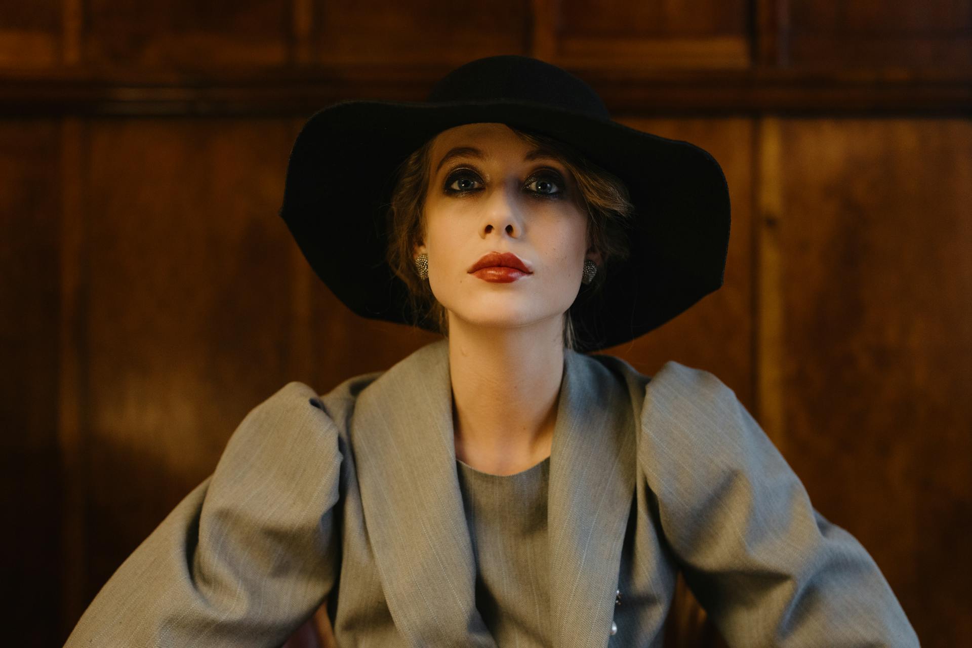 Una mujer seria con chaqueta gris y sombrero negro mirando al frente | Fuente: Pexels