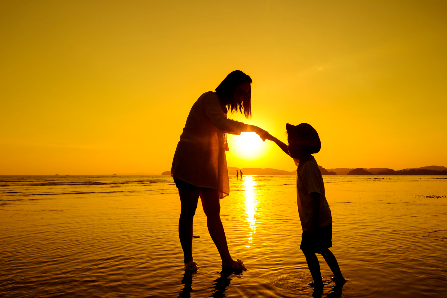 Una madre y su hijo en la playa al atardecer | Fuente: Freepik