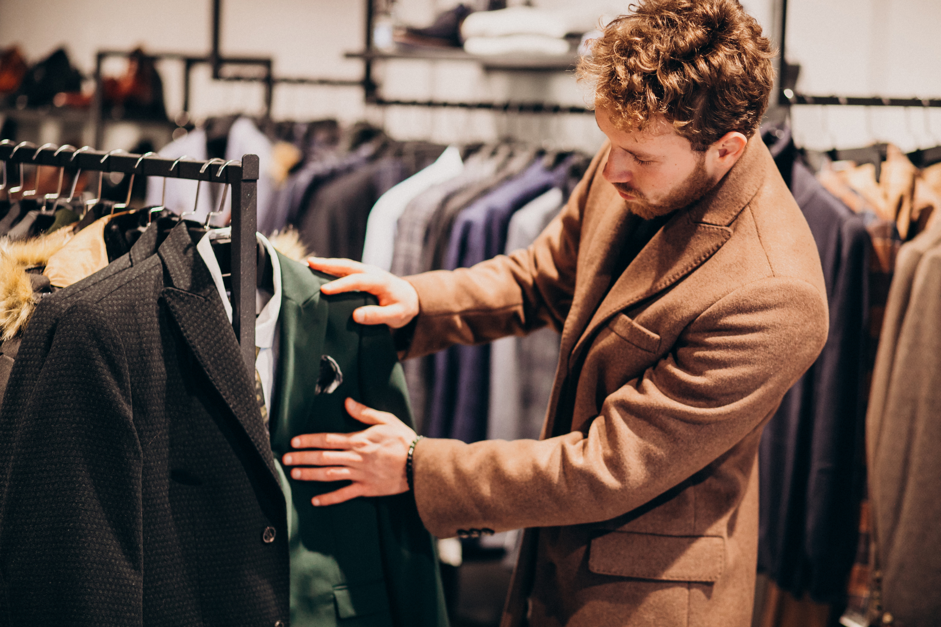 Un hombre mira con curiosidad unos trajes | Fuente: Freepik