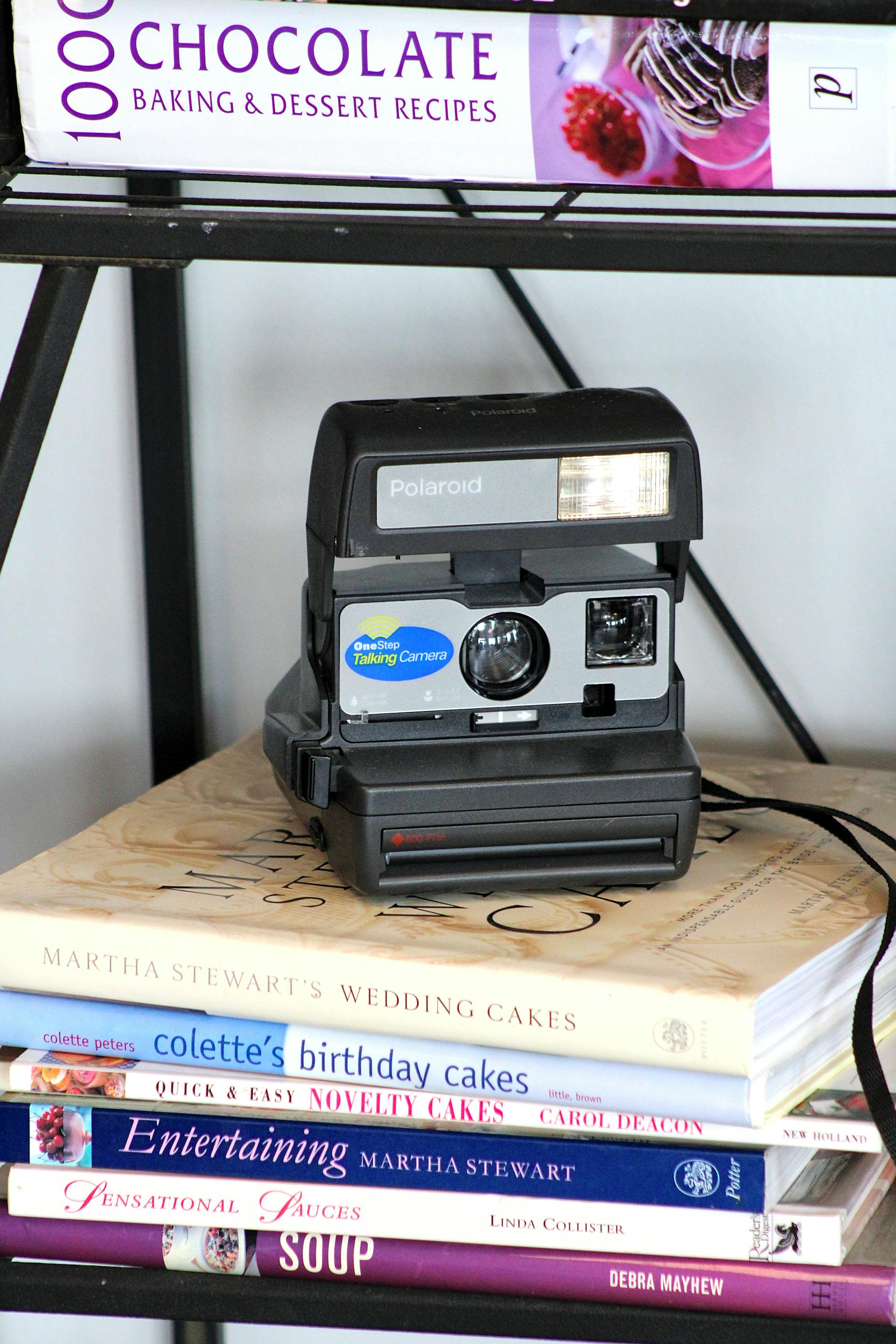 Una cámara polaroid vintage encima de unos libros de cocina | Fuente: Pexels