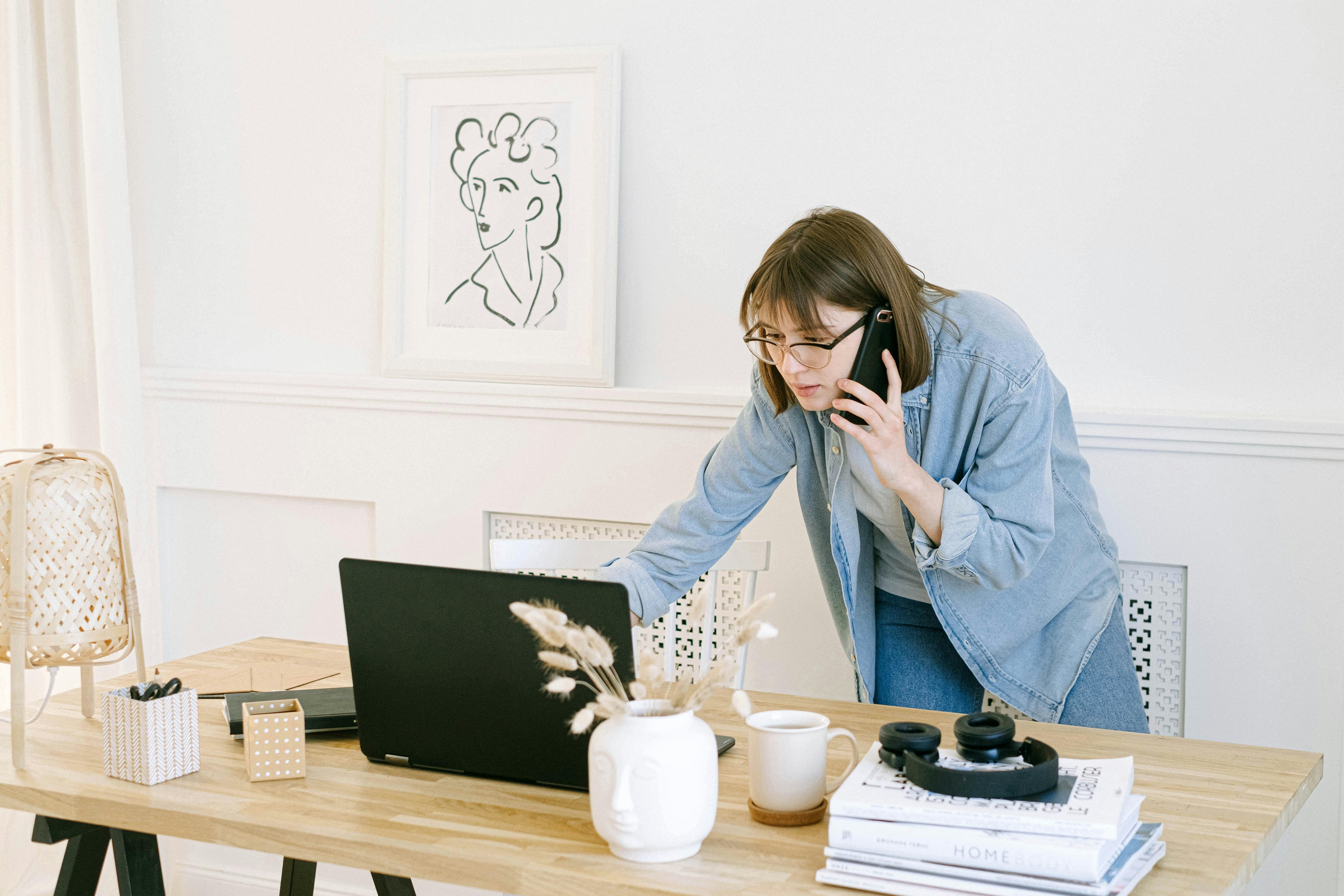 Mujer hablando por teléfono mirando un portátil | Fuente: Pexels