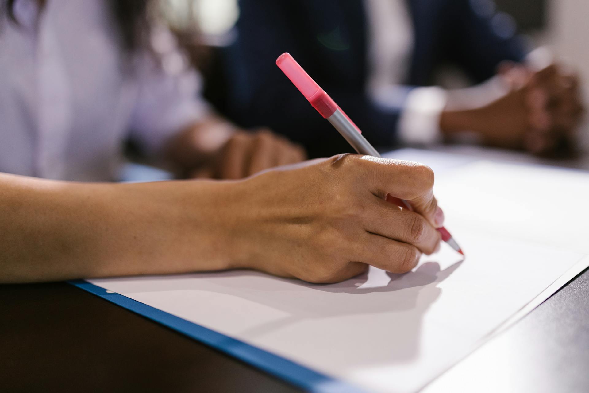 Una persona escribiendo en un papel | Fuente: Pexels