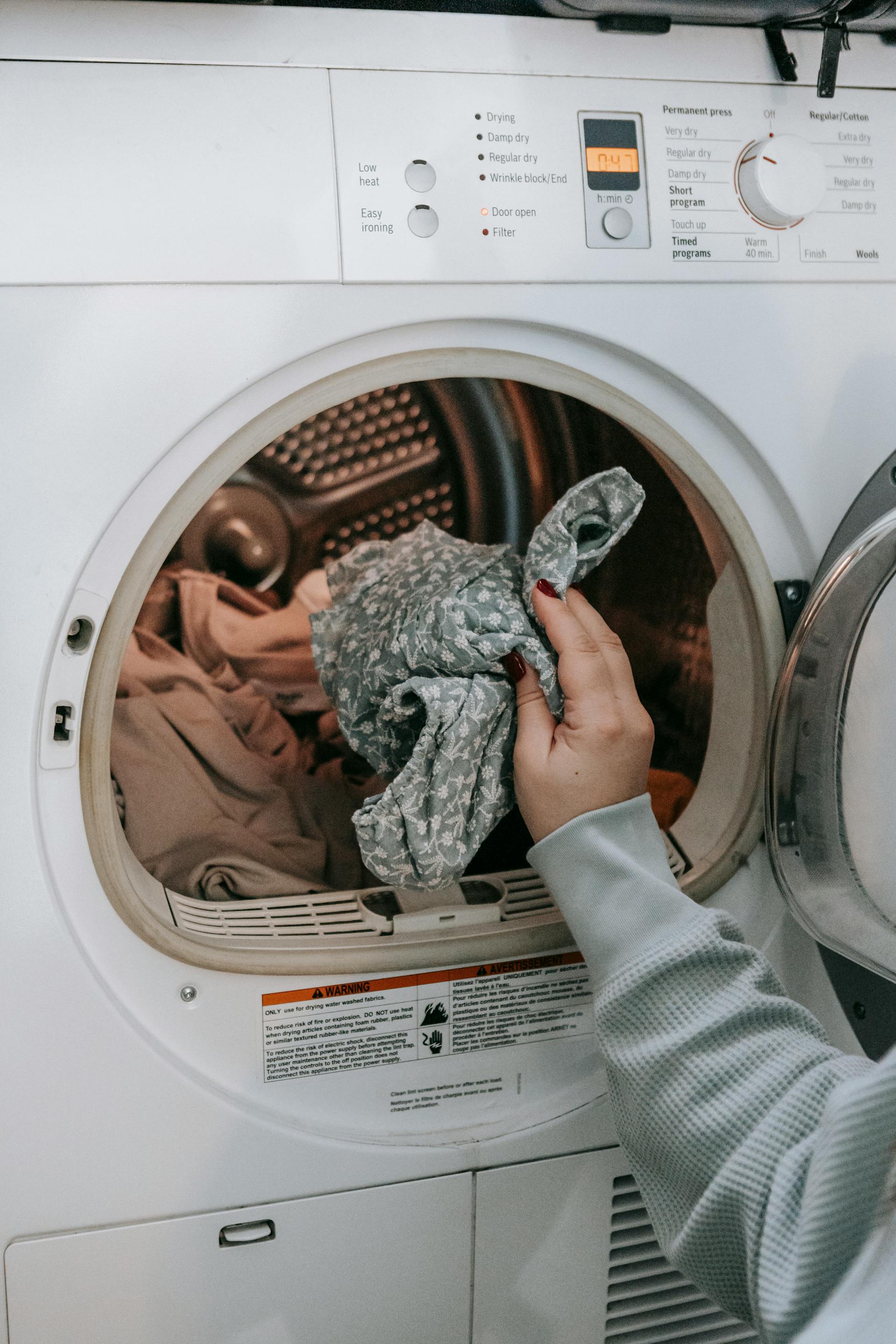 Una mujer poniendo ropa en una lavadora | Fuente: Pexels