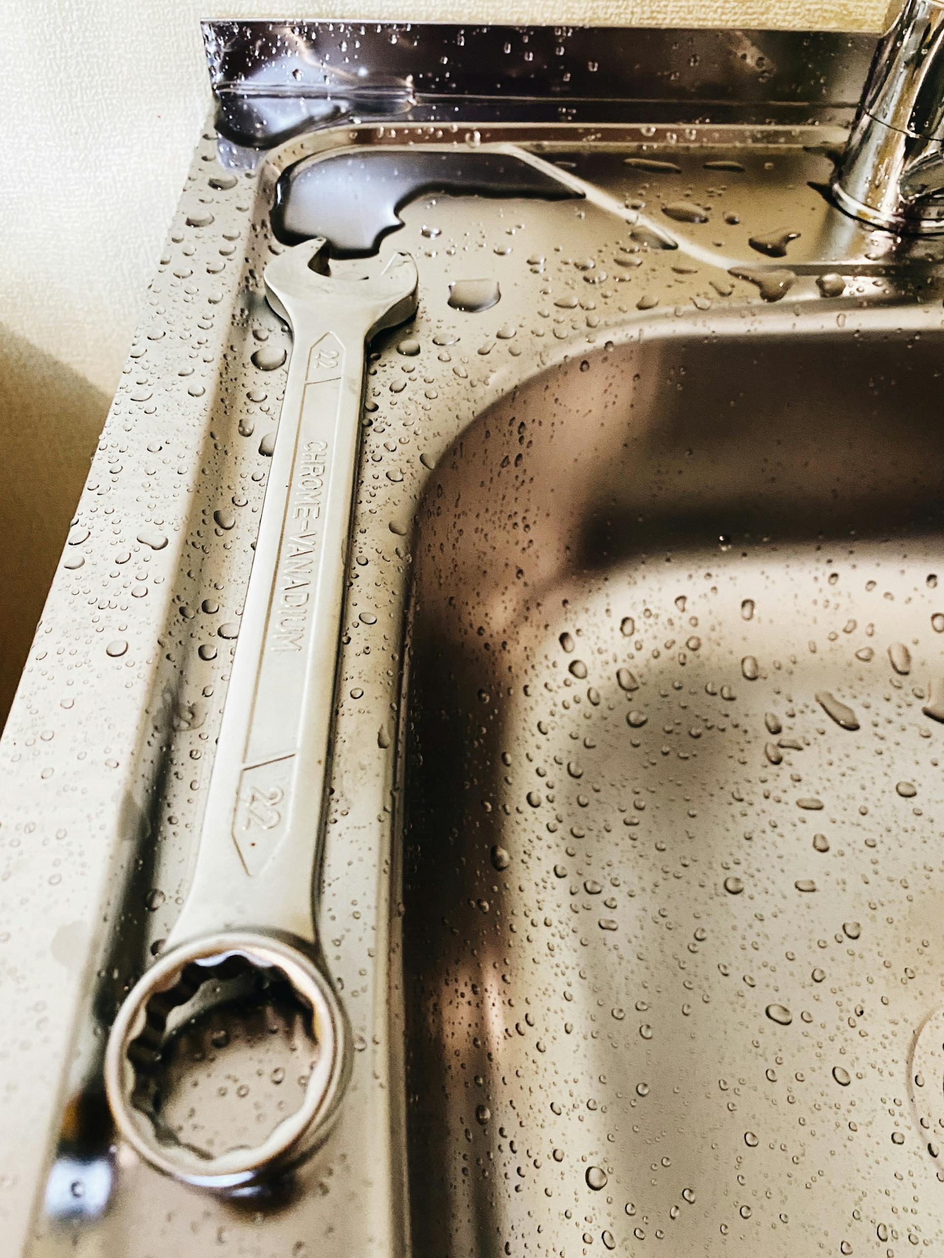 Llave inglesa tumbada sobre un fregadero de acero inoxidable | Fuente: Pexels
