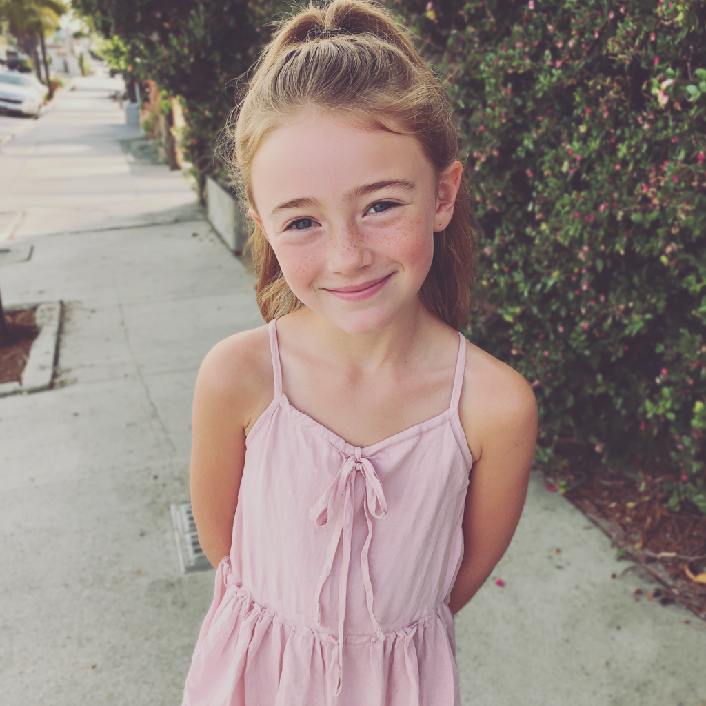 Una niña sonriente de pie en una acera | Fuente: Midjourney