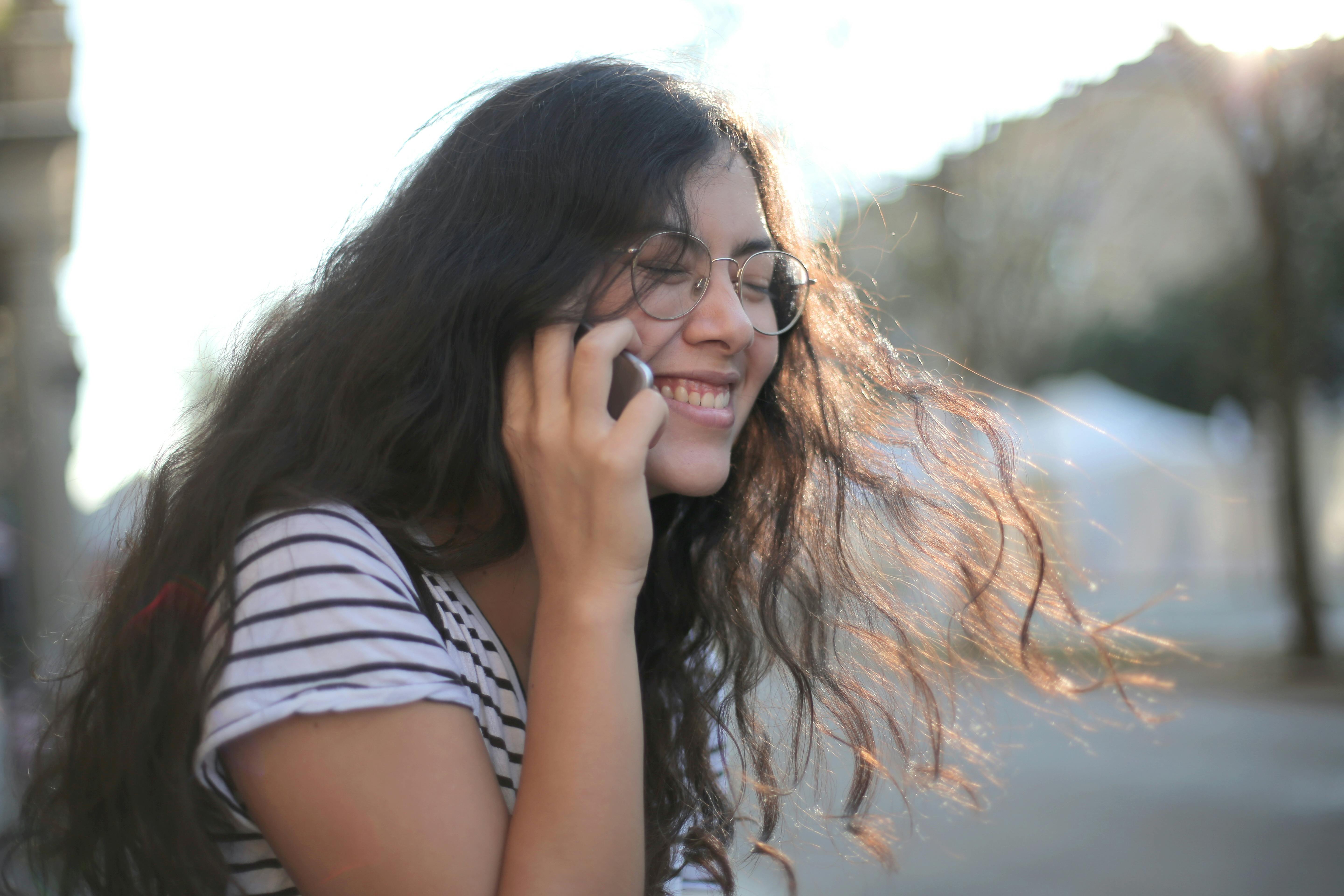 Una chica riendo durante una llamada | Fuente: Pexels