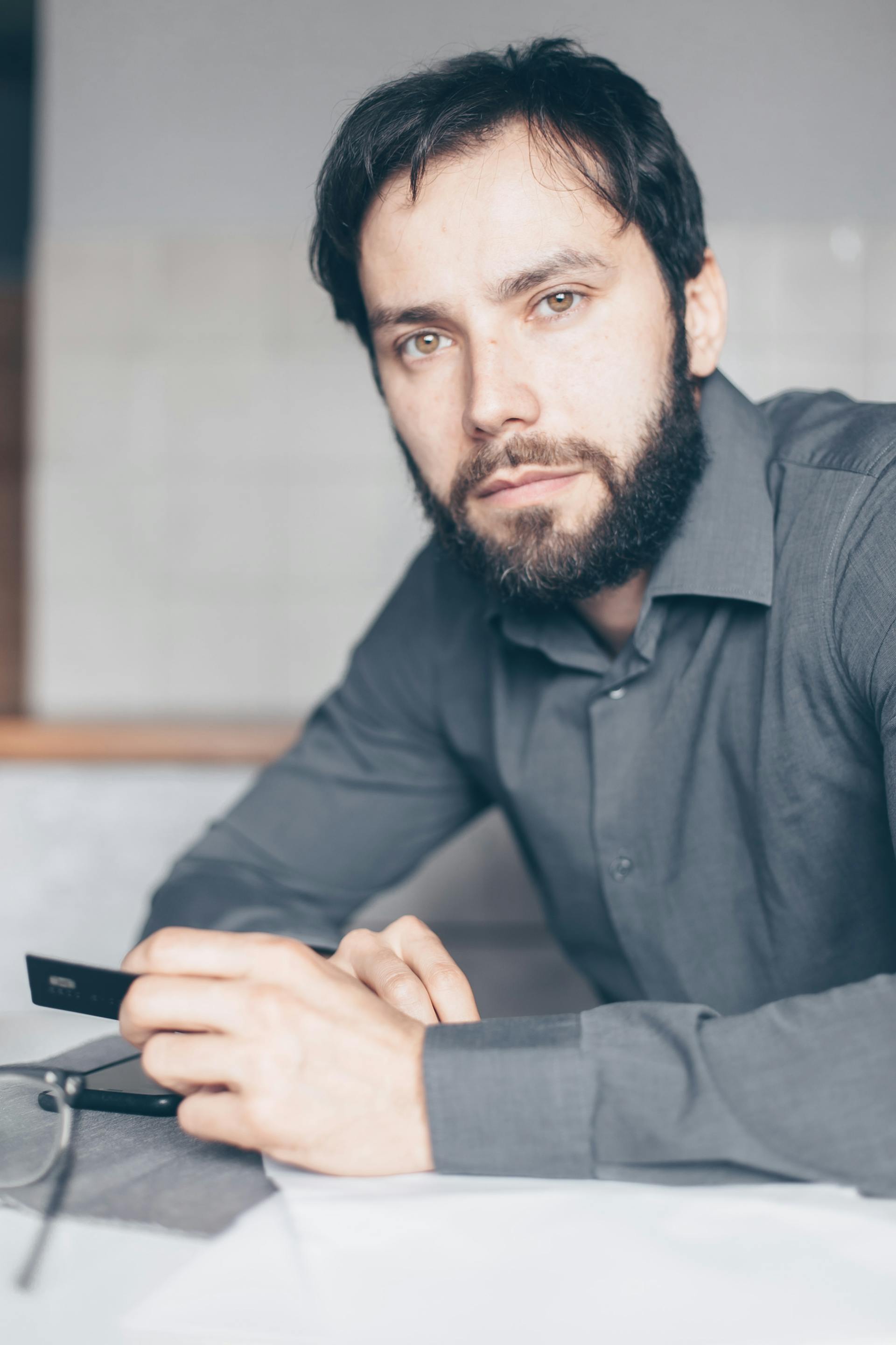 Un hombre con camisa de vestir gris mirando a alguien | Fuente: Pexels
