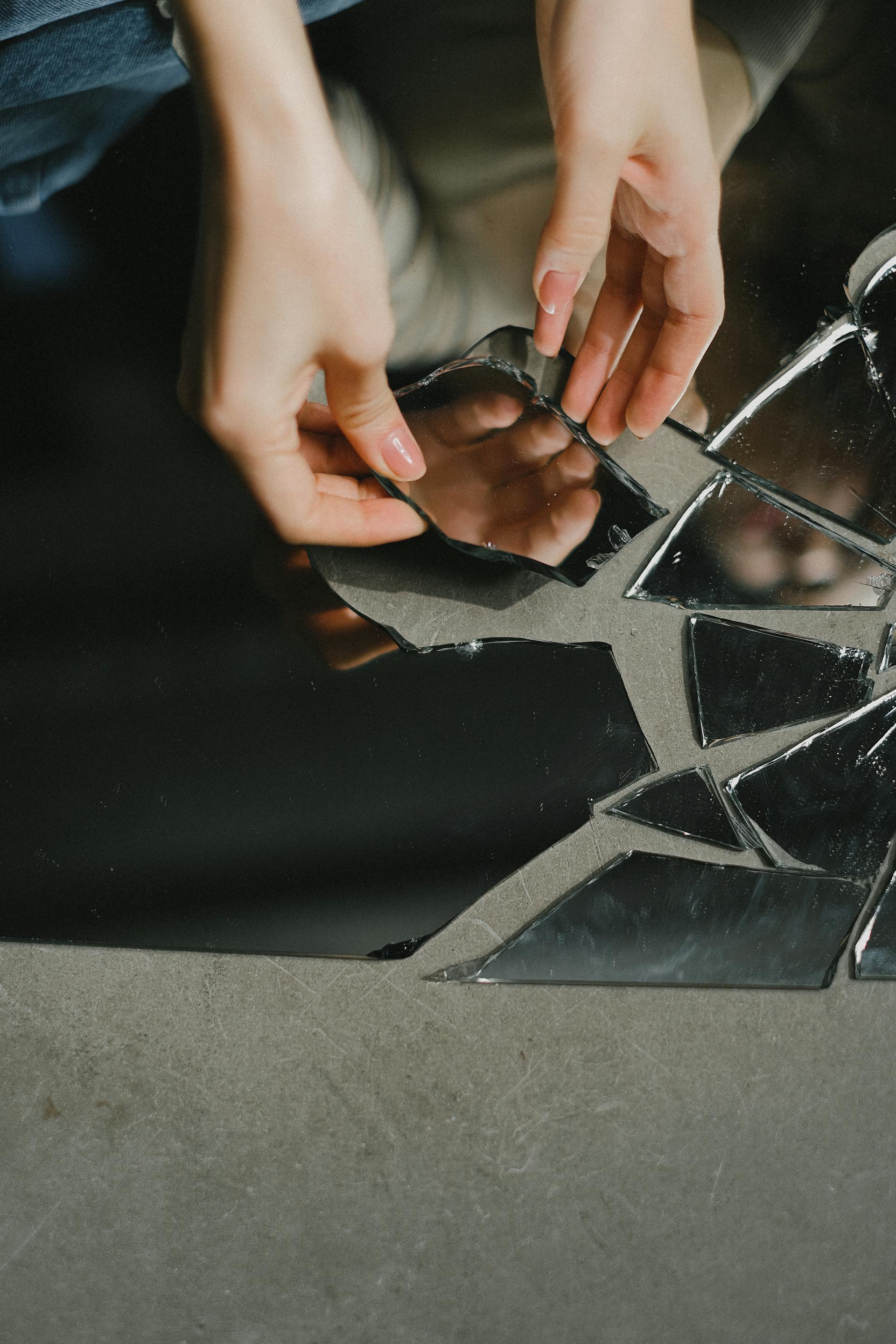 Una mujer tocando un trozo de espejo roto | Fuente: Pexels