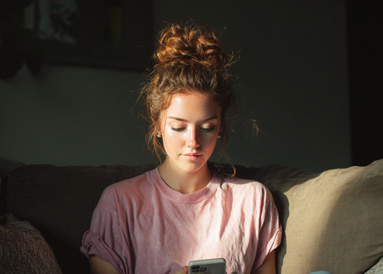 Una mujer sentada en un sofá y utilizando su teléfono | Fuente: Midjourney