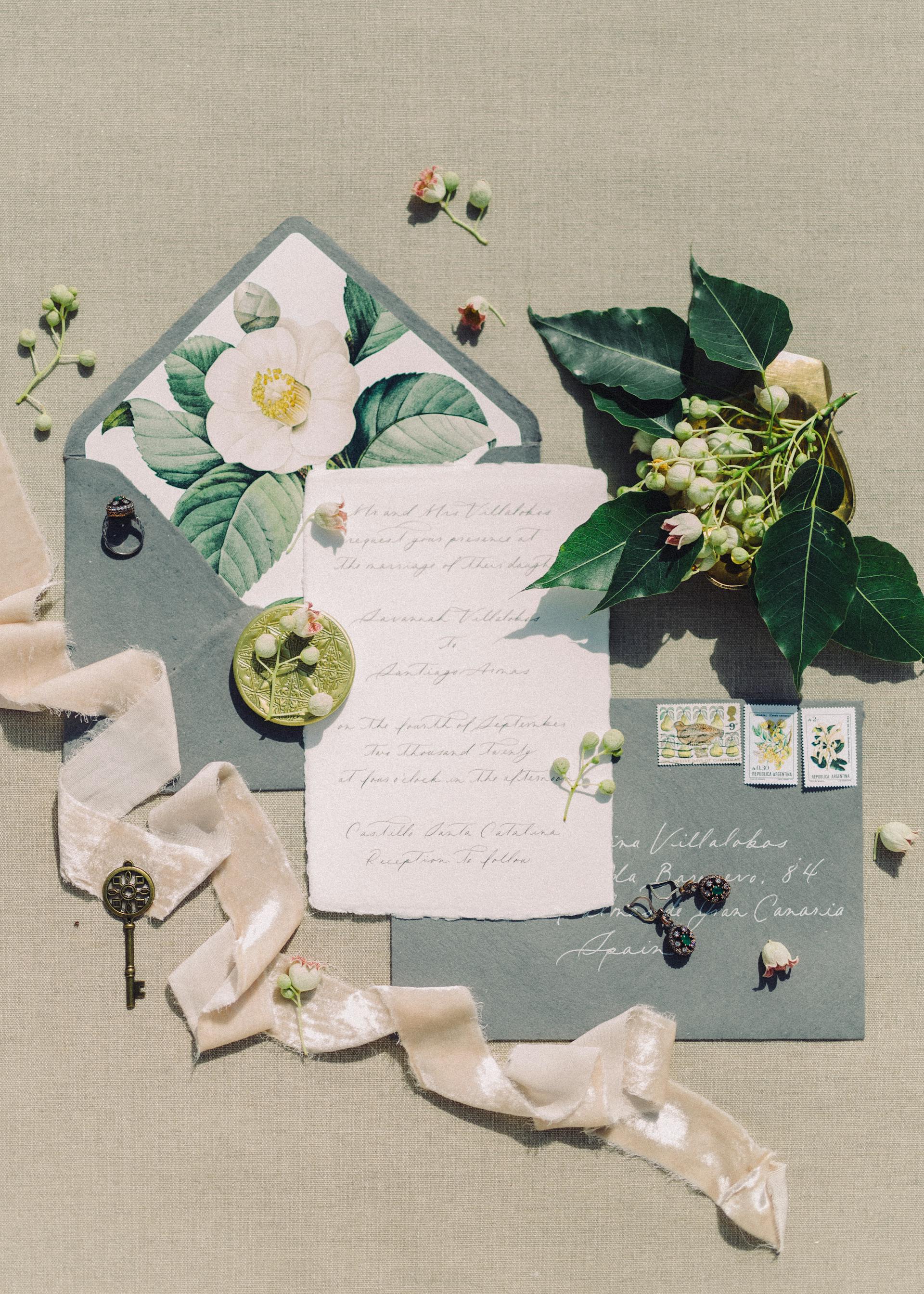 Invitación de boda de estilo vintage con sobre, lazo, flores y sellos sobre una tela beige | Fuente: Pexels