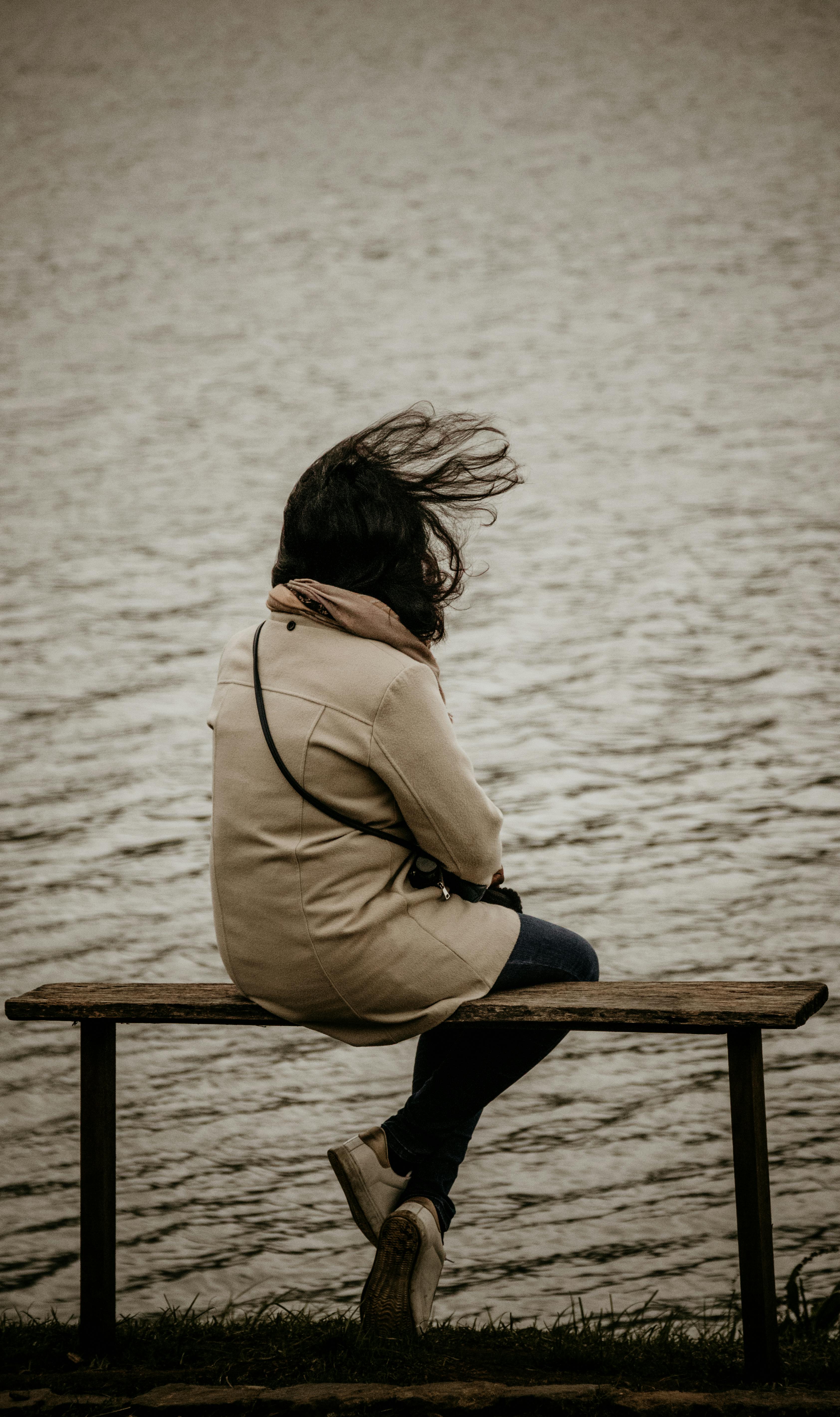 Mujer sentada en un banco junto al lago | Fuente: Pexels