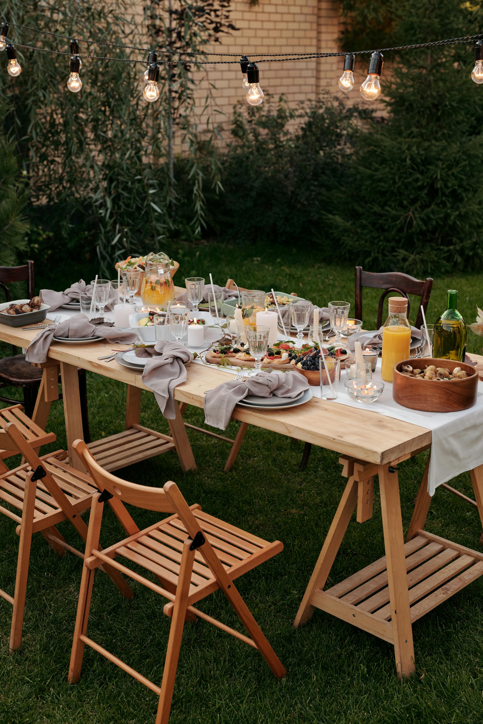 Cena servida en una mesa de madera marrón con sillas en un patio delantero | Fuente: Pexels