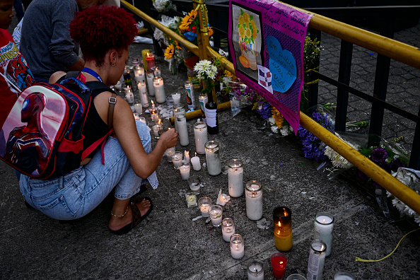 Una mujer enciende una vela mientras amigos y familiares rinden homenaje a las víctimas frente a la discoteca Jet Set en Santo Domingo, el 11 de abril de 2025 | Fuente: Getty Images