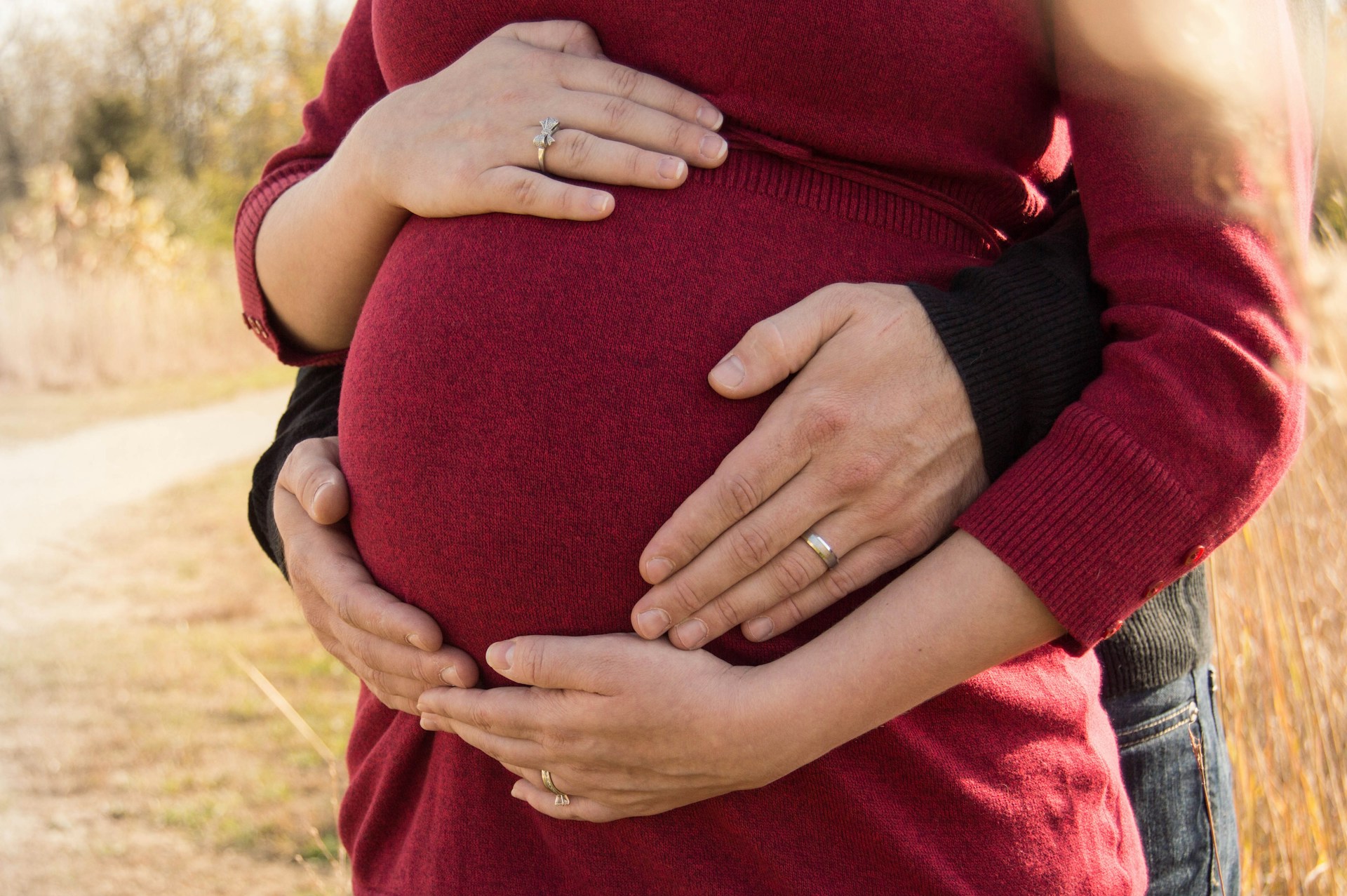 Un hombre abraza a su pareja embarazada por detrás | Fuente: Unsplash