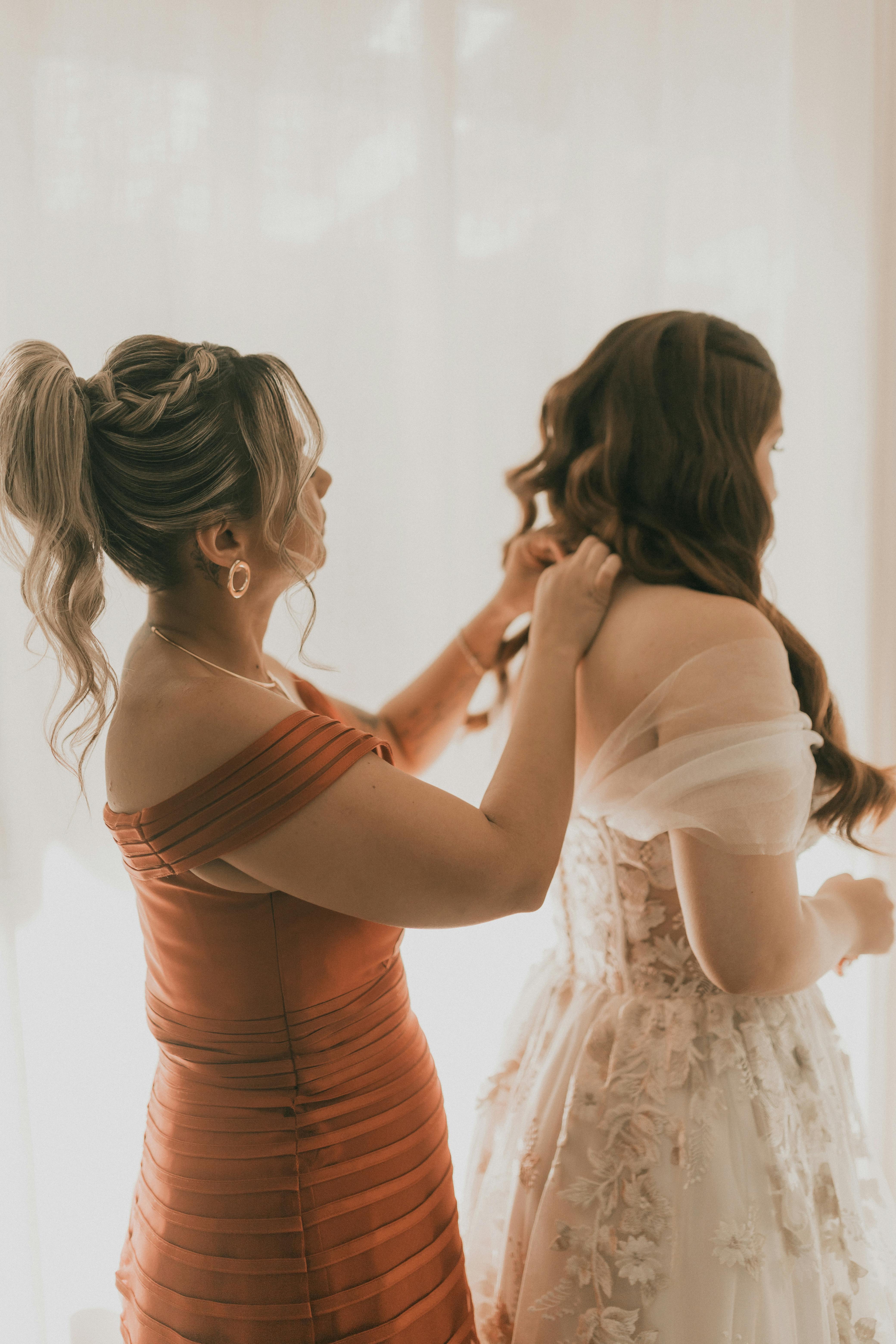 Una dama de honor ayudando a una novia | Fuente: Pexels