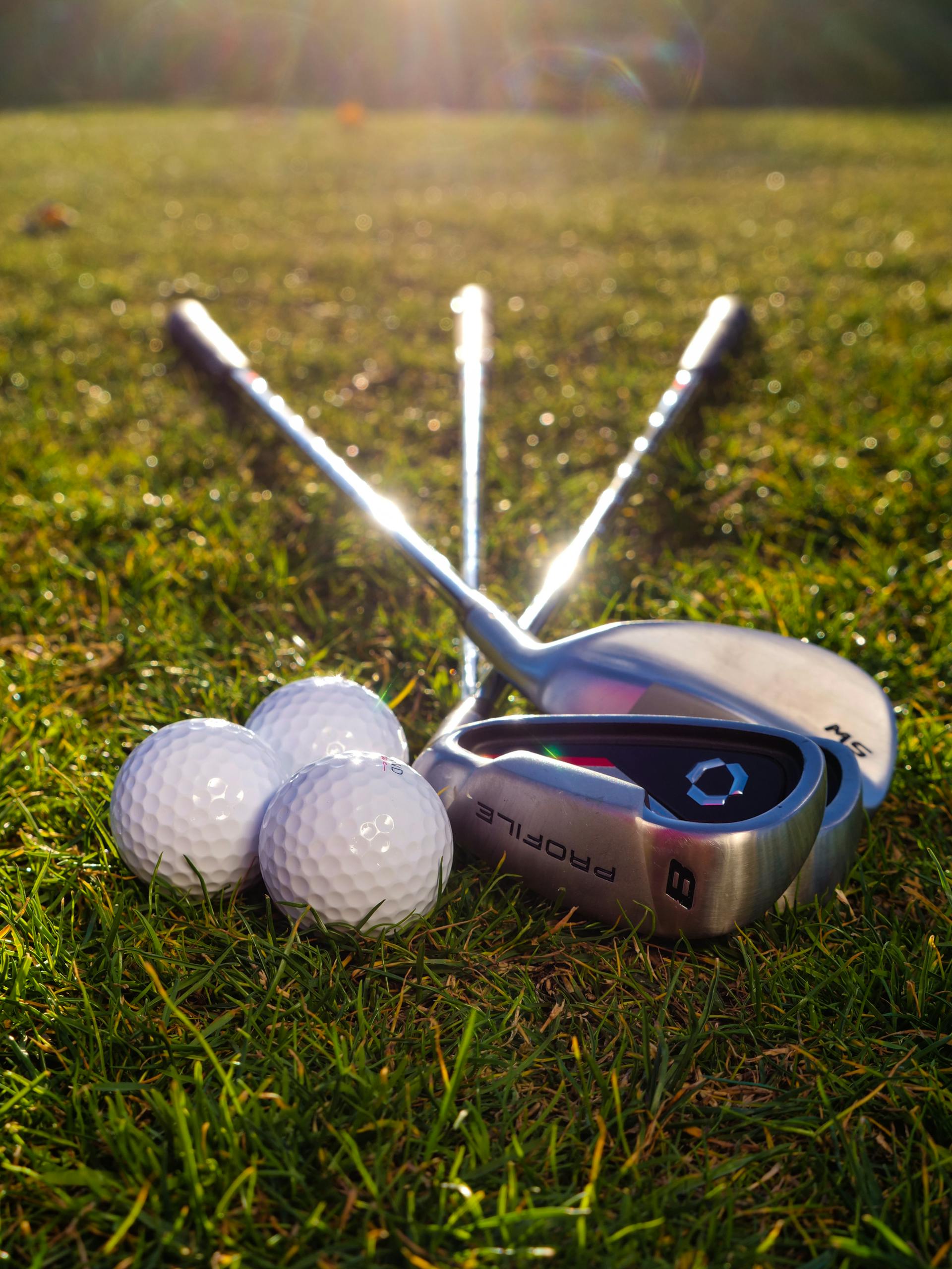 Pelotas y palos de golf tirados en la hierba | Fuente: Pexels