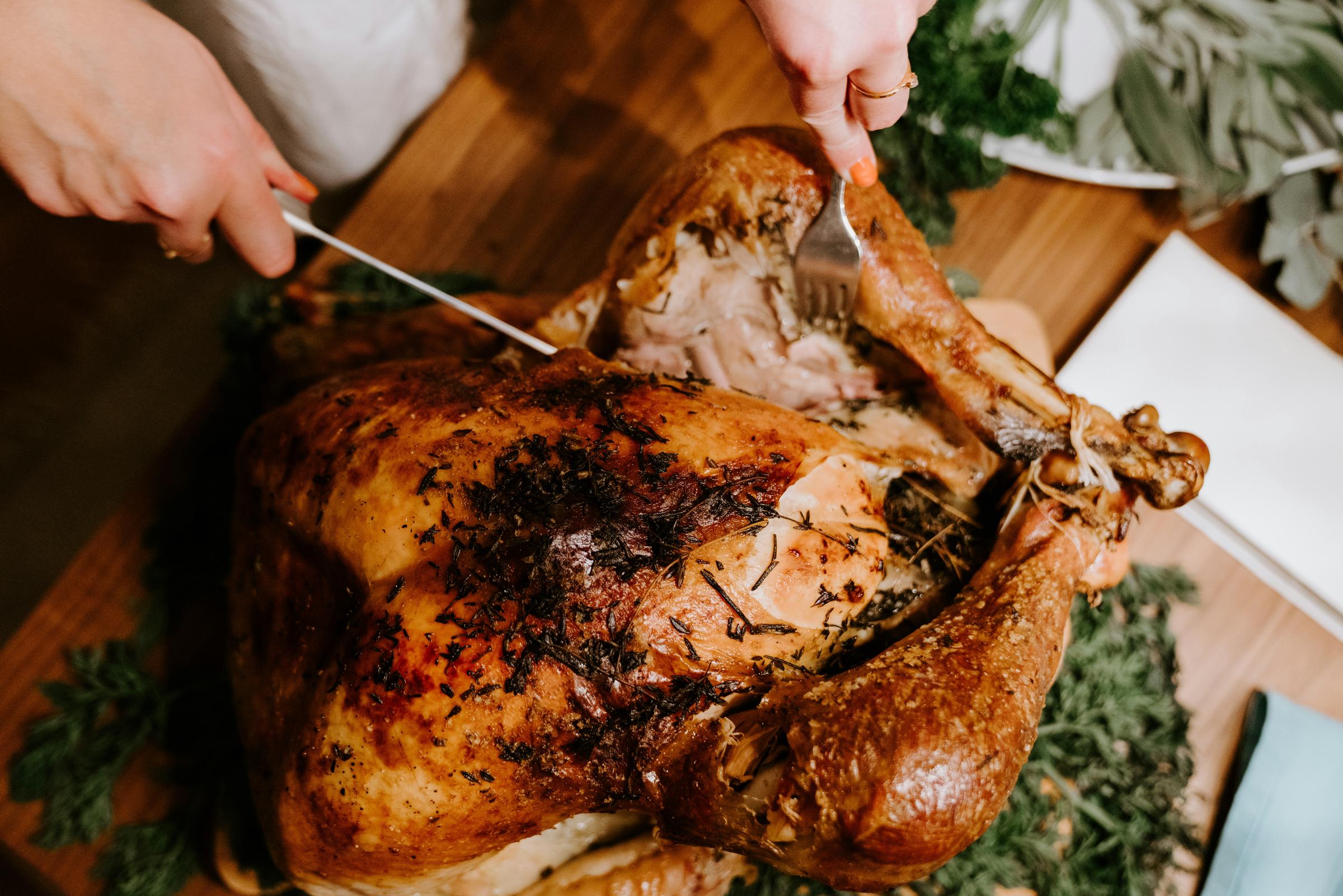 Una persona cortando un pollo asado | Fuente: Unsplash