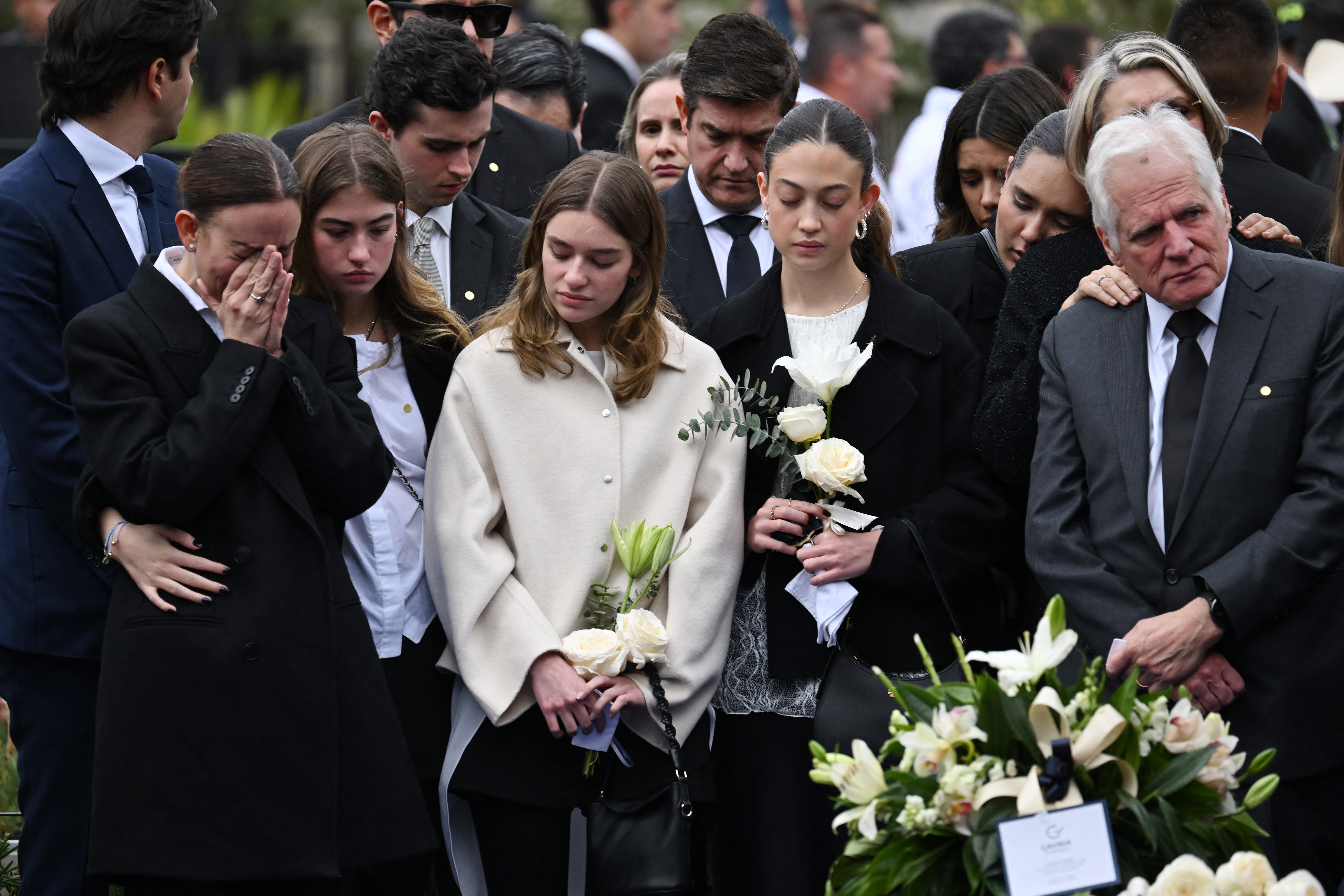 Miguel Uribe Londoño (der.) y María Claudia Tarazona (izq.), padre y viuda del candidato presidencial colombiano asesinado Miguel Uribe, junto con otros familiares, lloran mientras observan el ataúd de su ser querido durante su entierro en el Cementerio Central de Bogotá el 13 de agosto de 2025. | Fuente: Getty Images.