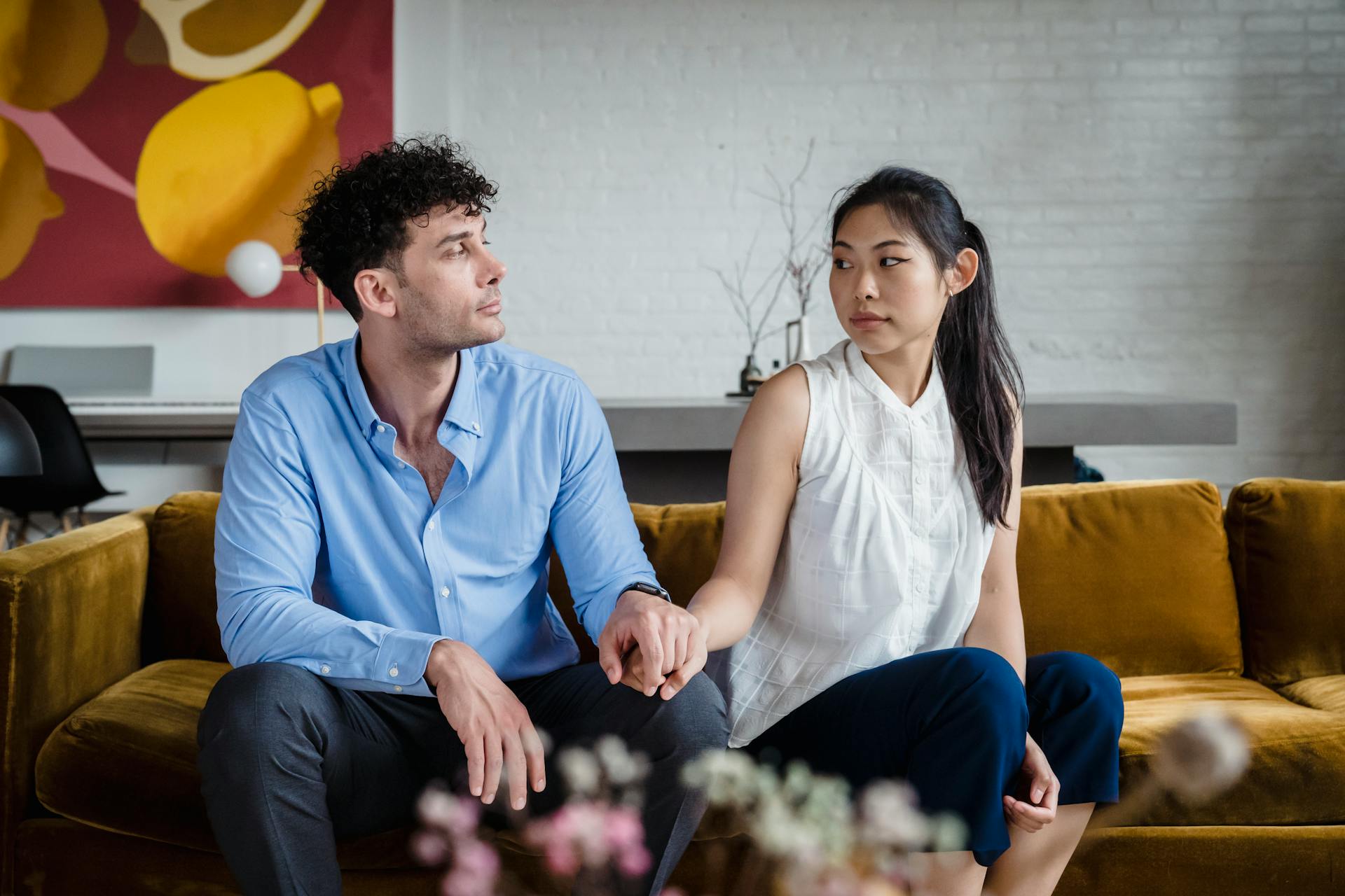 Una pareja tomada de la mano sentada en un sofá | Fuente: Pexels
