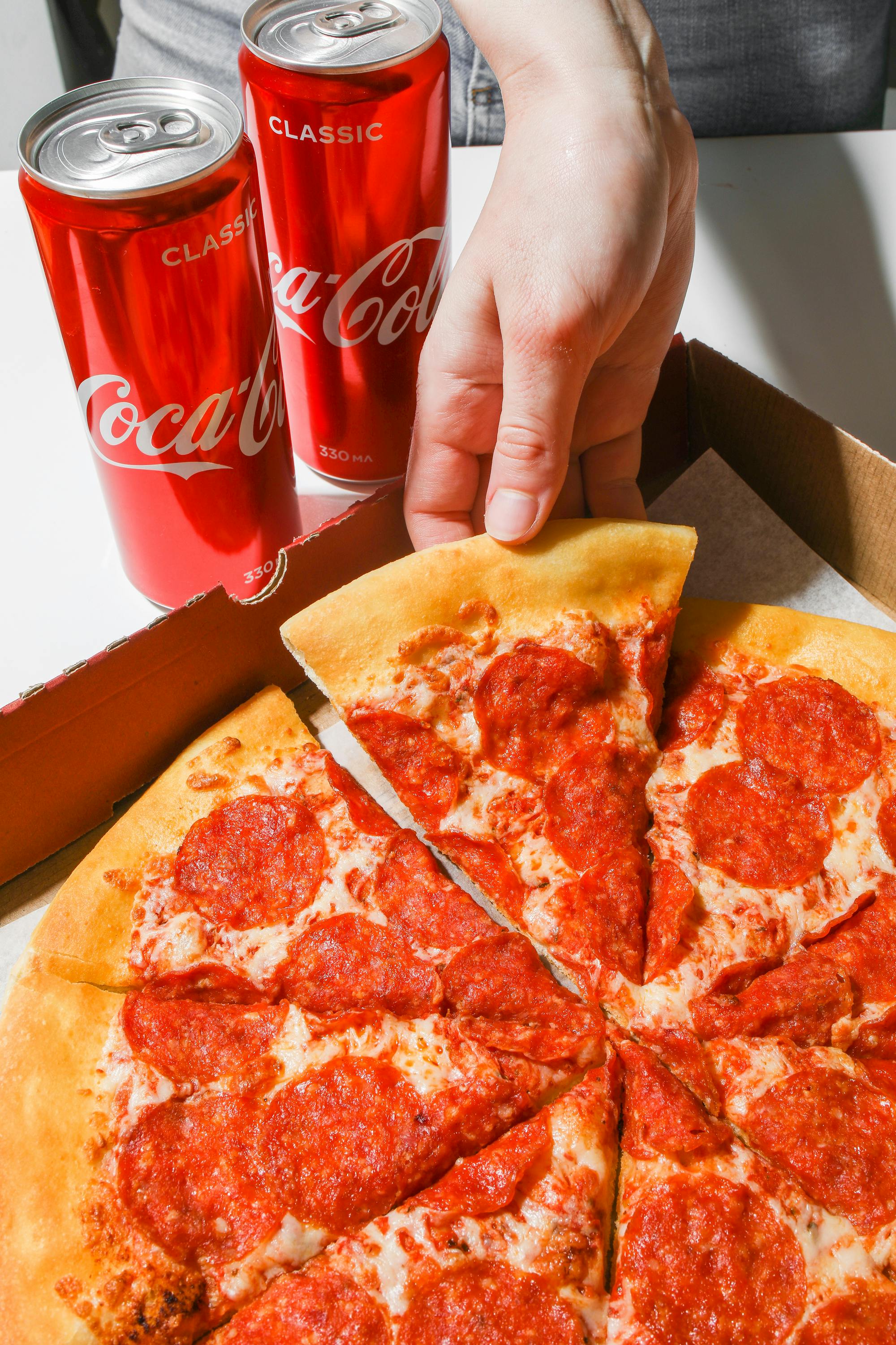 Una persona tomando una porción de pizza | Fuente: Pexels