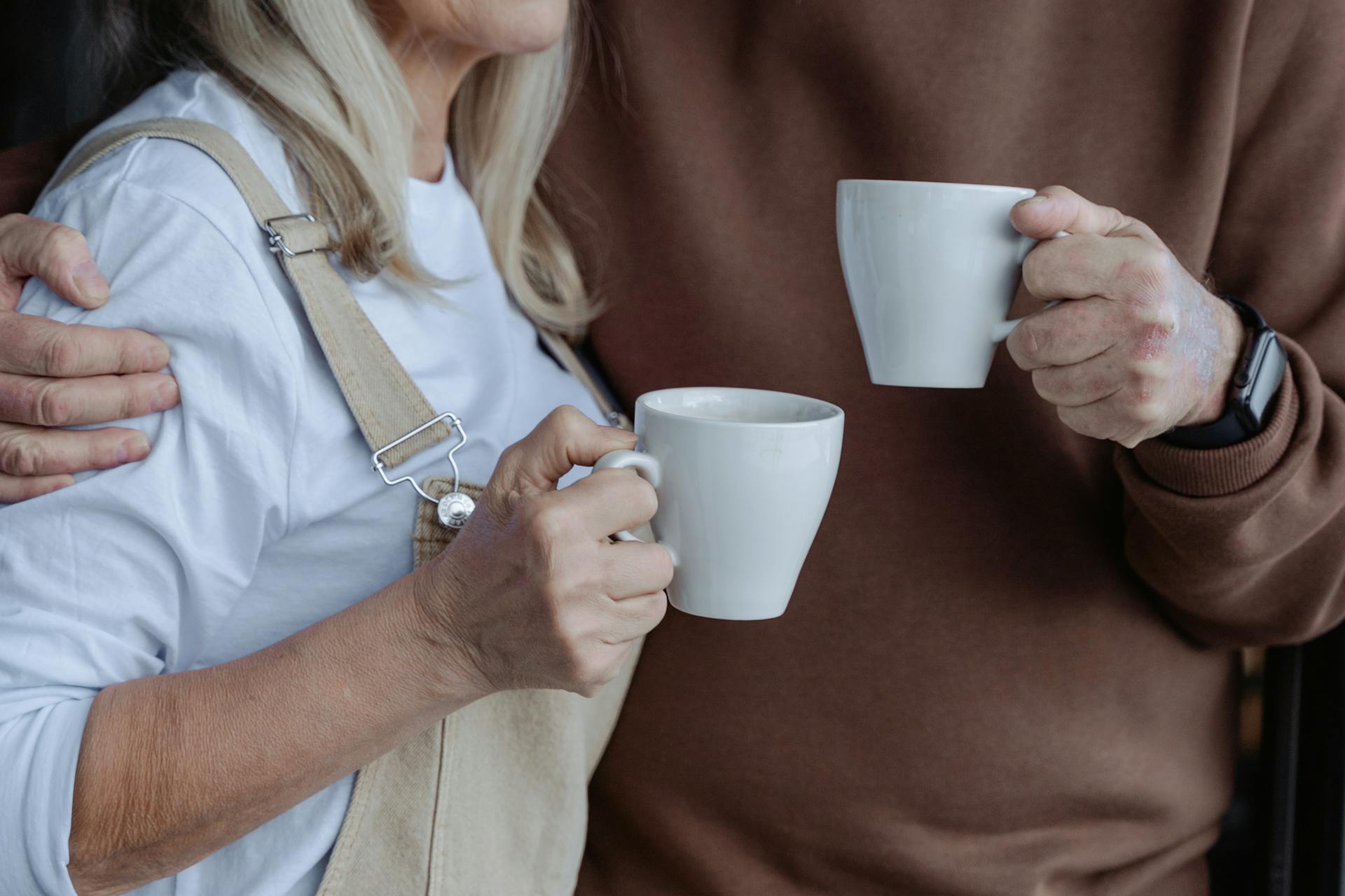 Primer plano de una pareja sosteniendo tazas blancas | Fuente: Pexels