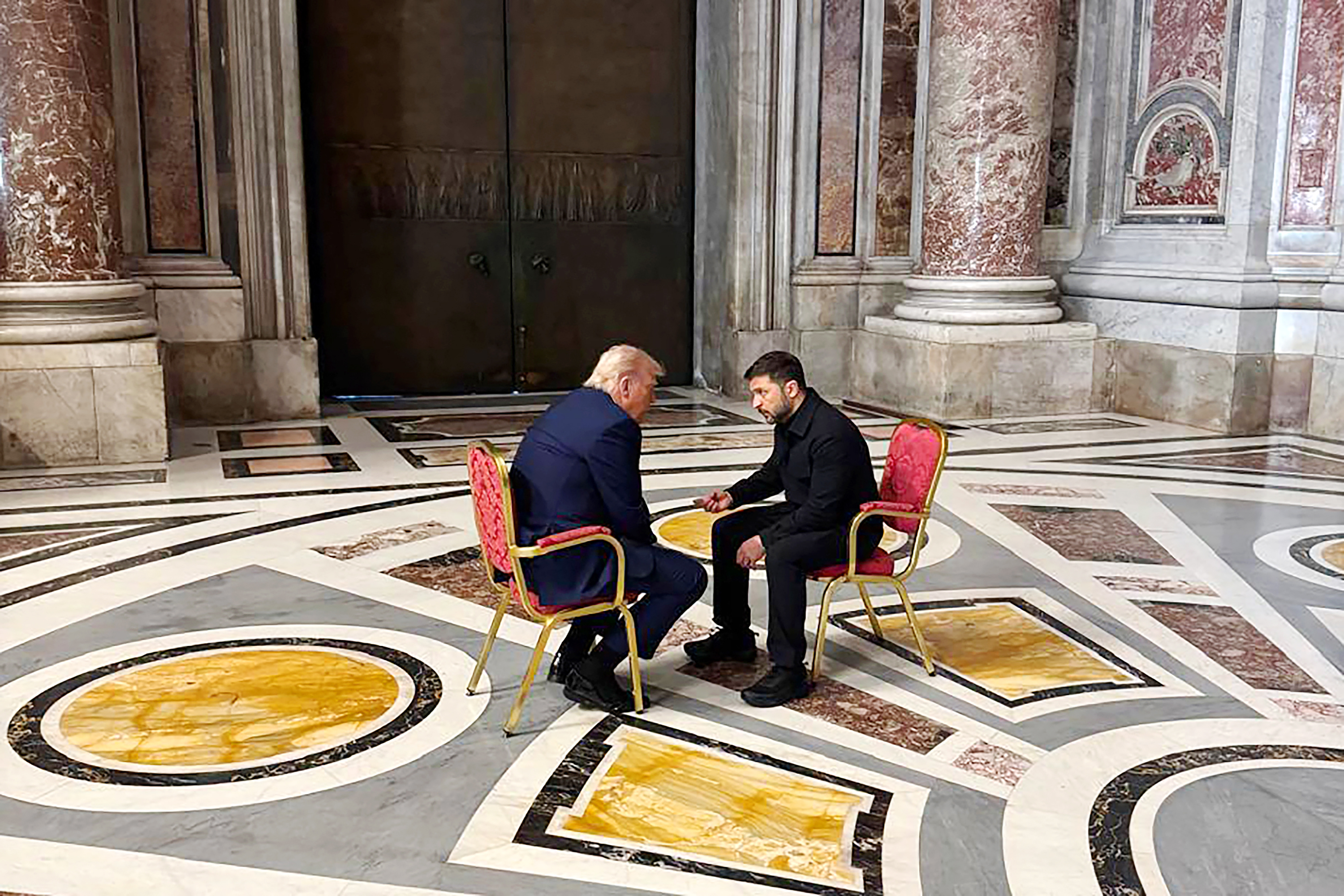 El presidente de Ucrania, Volodymyr Zelensky, y Donald están sentados uno frente al otro, sumidos en una profunda conversación, en lo que parece ser una sala del Vaticano durante el funeral del papa Francisco.