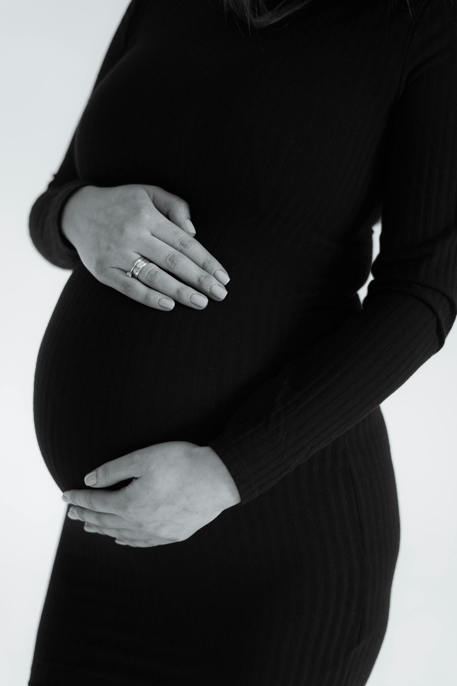 Foto en escala de grises de una mujer sujetando su barriguita | Fuente: Pexels