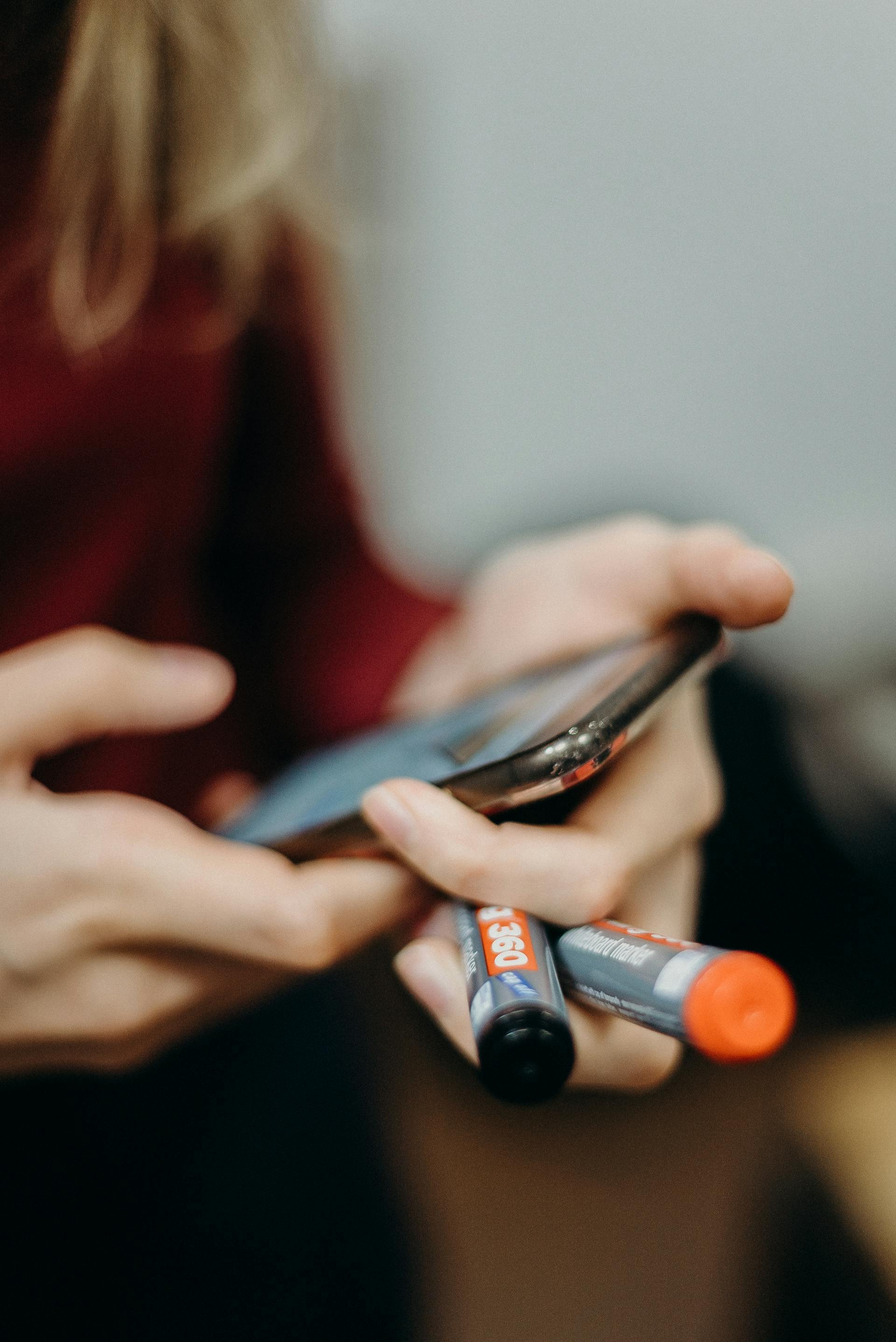 Una mujer con un smartphone y dos marcadores | Fuente: Pexels