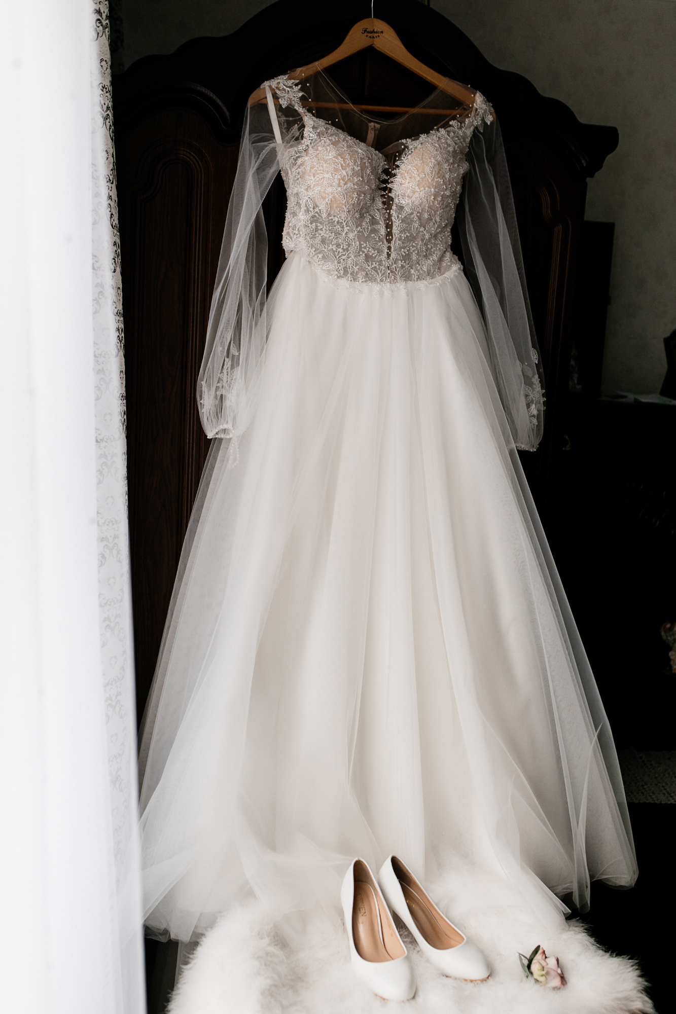 Un vestido de novia en una percha y unos tacones blancos sobre un puf de piel | Fuente: Freepik