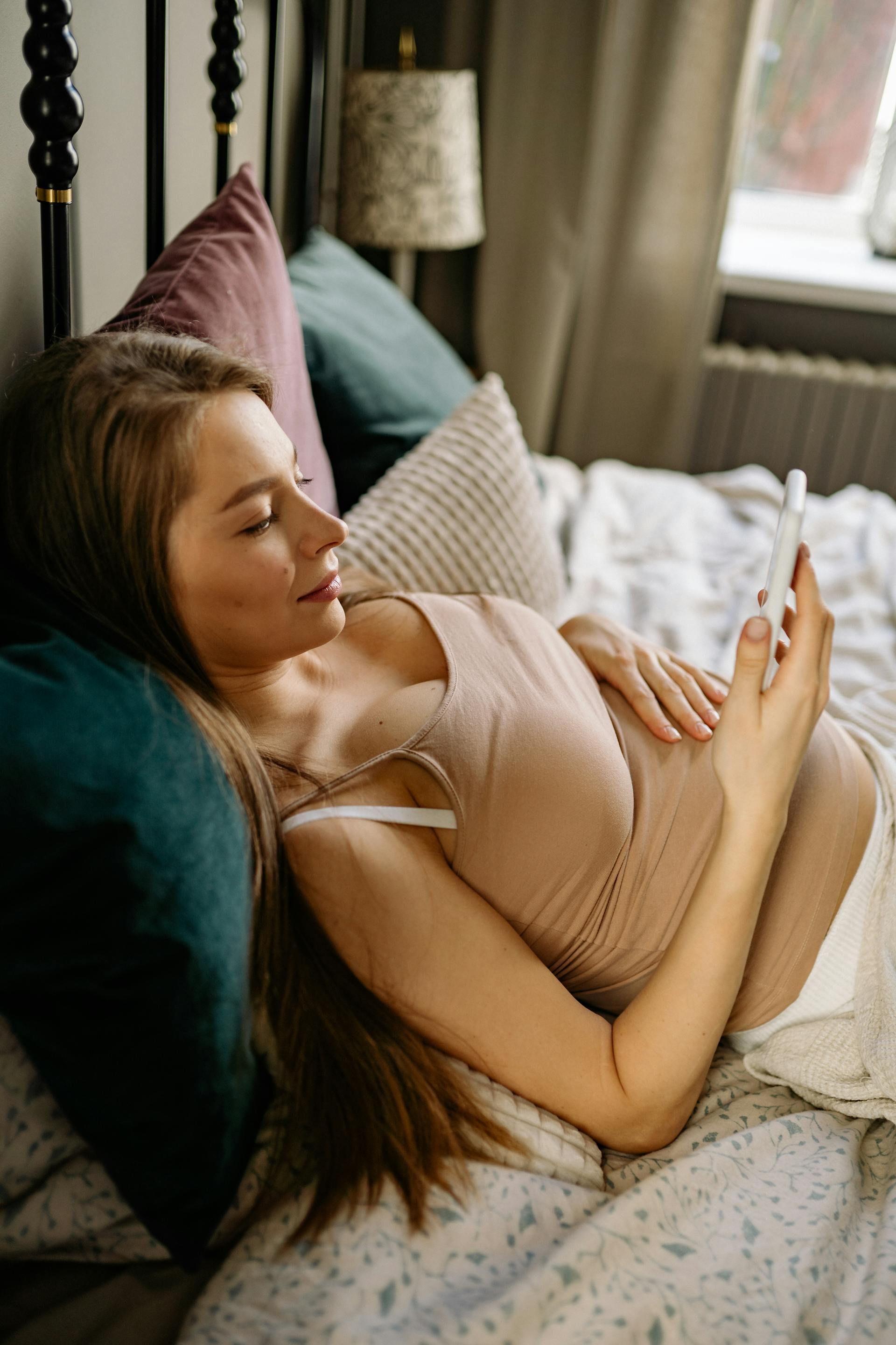 Una joven relajándose en una cama | Fuente: Pexels