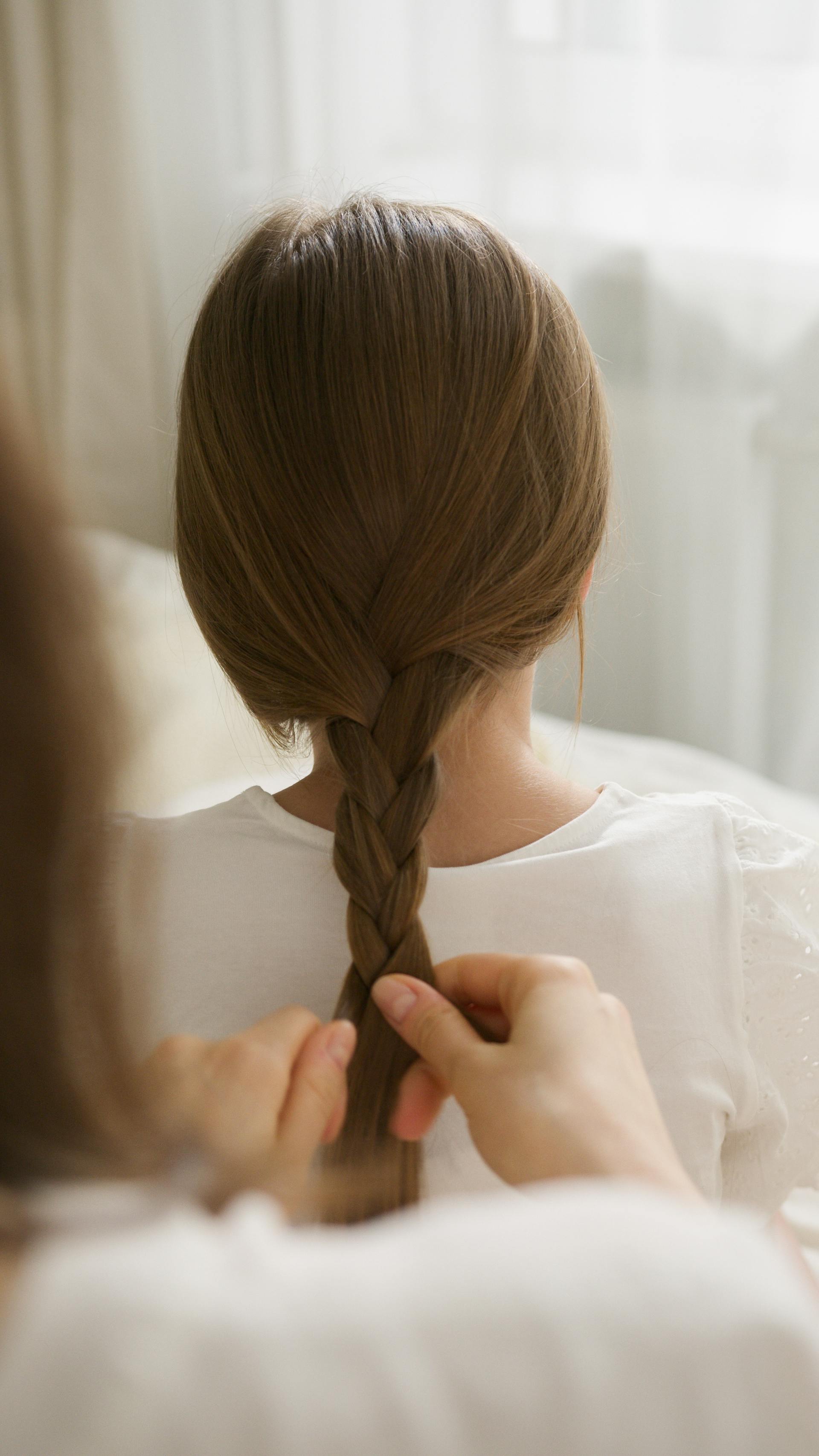 Primer plano de una mujer trenzando el pelo de su hija | Fuente: Pexels