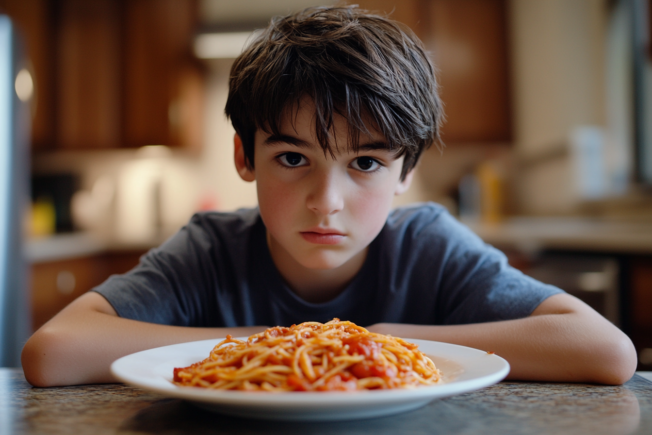 A sullen-looking teenager sitting at the kitchen table | Source: Midjourney
