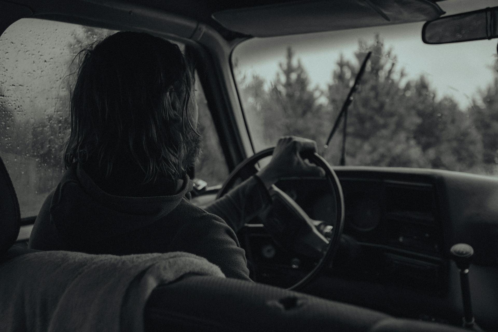 Foto en escala de grises de una mujer conduciendo bajo la lluvia | Fuente: Pexels