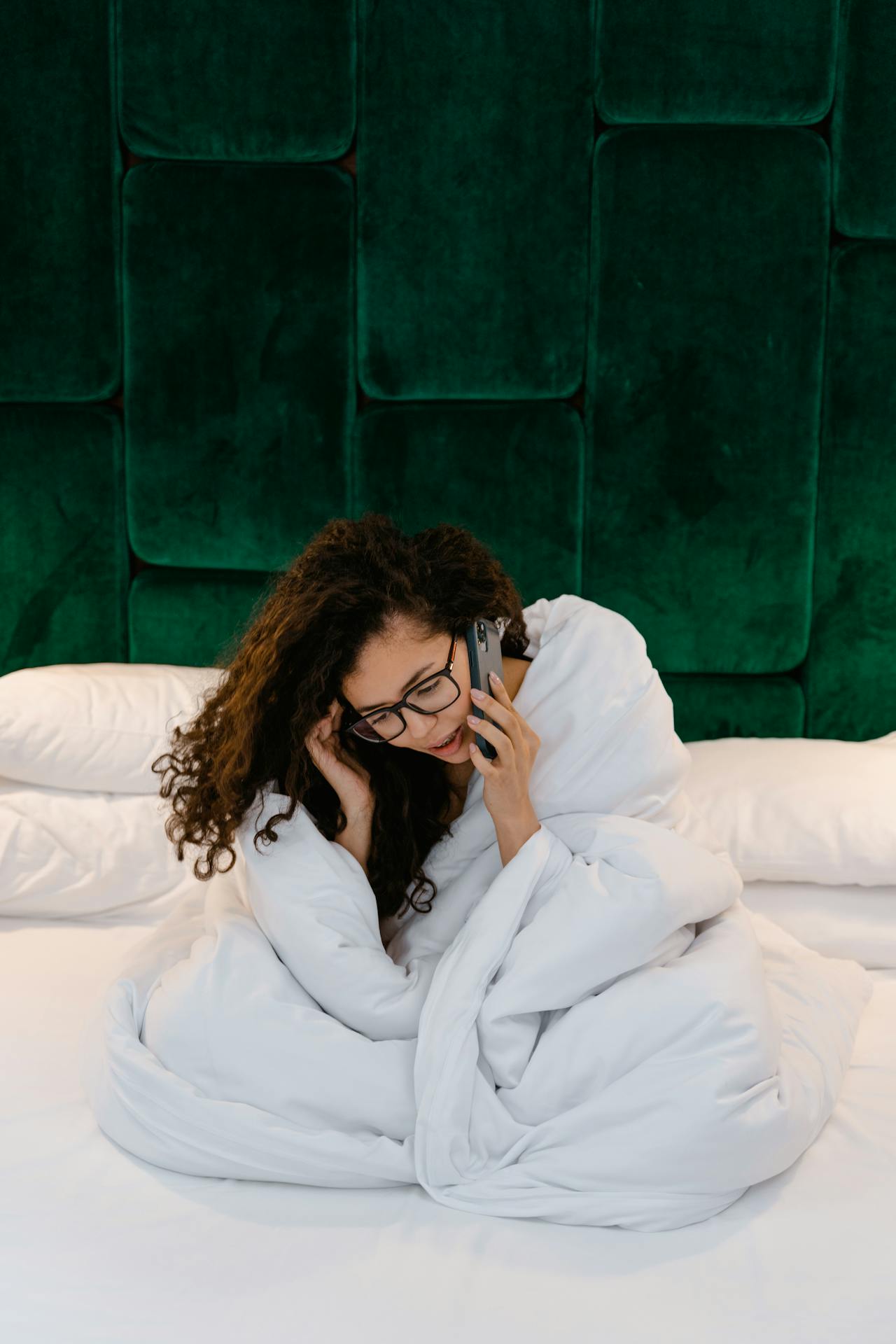 Una mujer sentada en su cama y hablando por teléfono | Fuente: Pexels