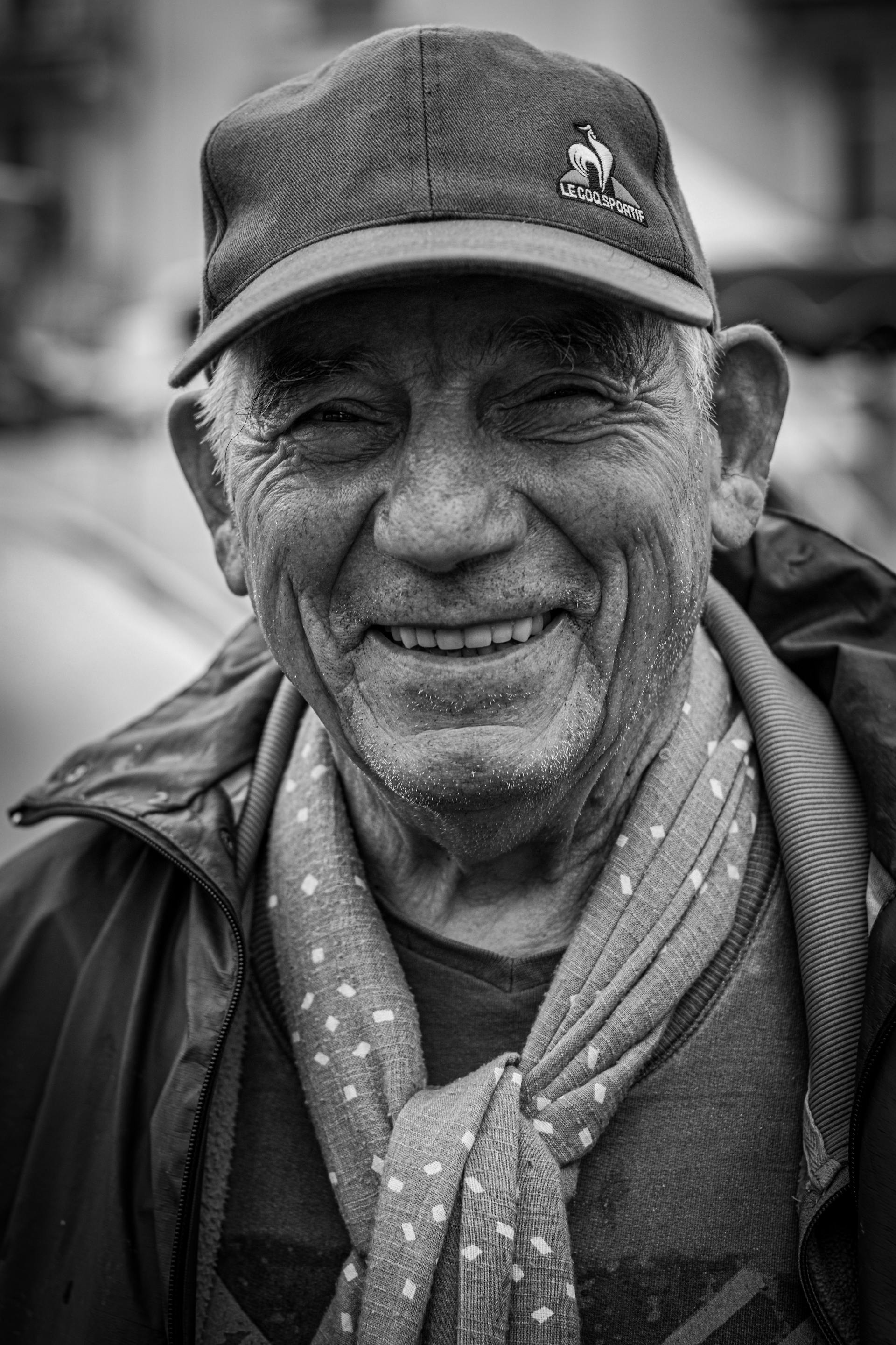 Foto en escala de grises de un hombre sonriente con gorra | Fuente: Pexels