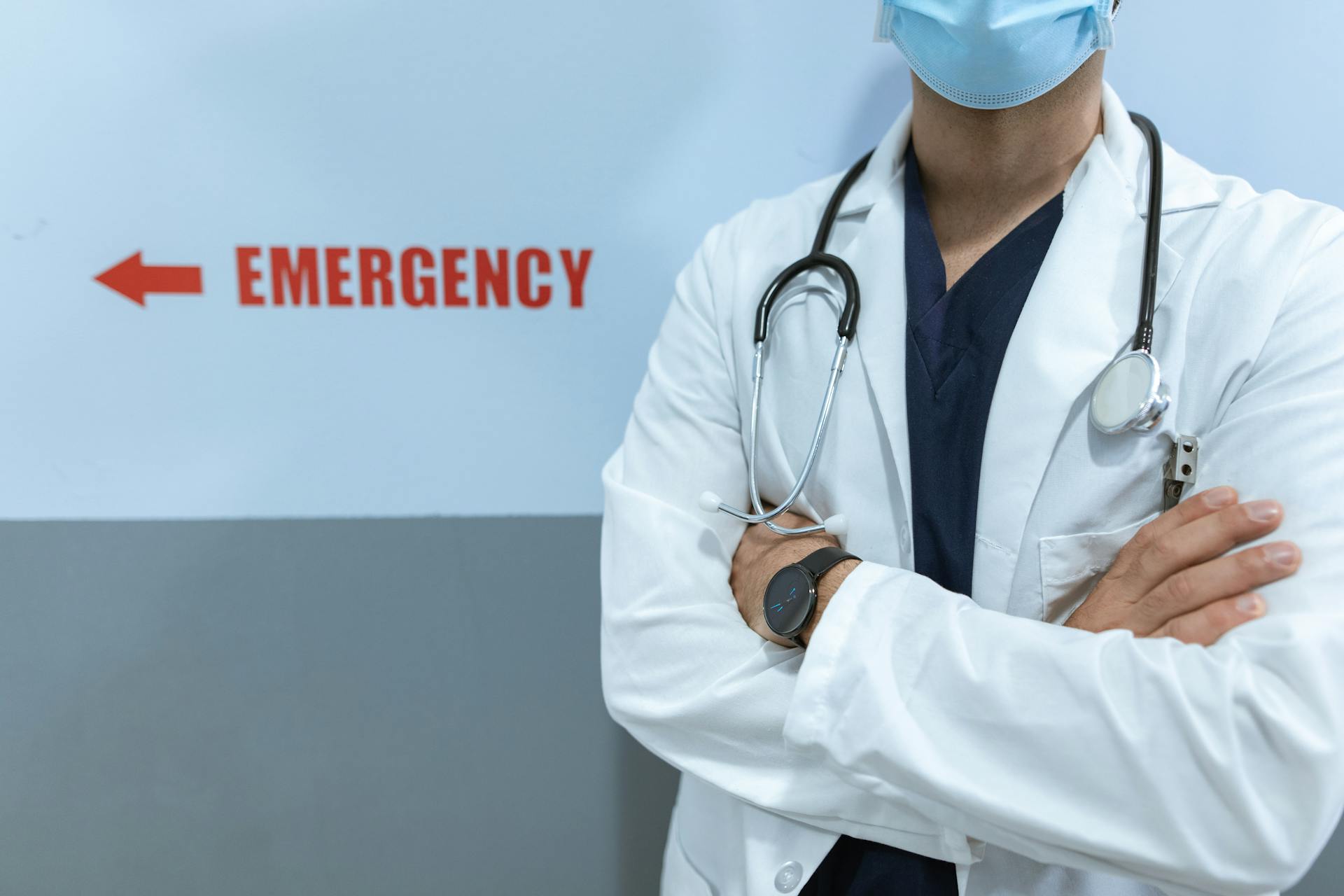 Un médico junto a la señal de emergencia en la pared | Fuente: Pexels