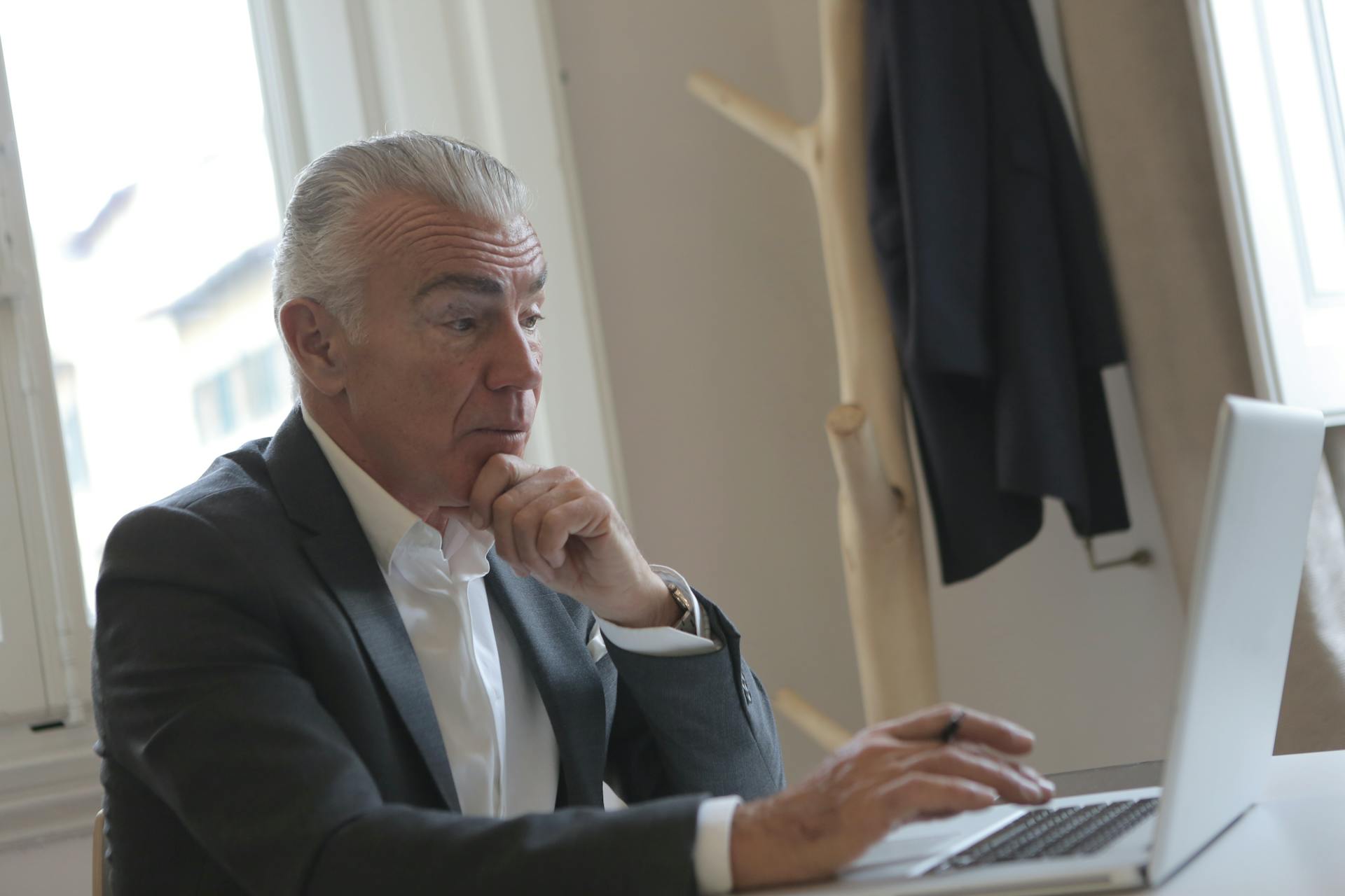 Un elegante hombre mayor utilizando su portátil en su despacho | Fuente: Pexels