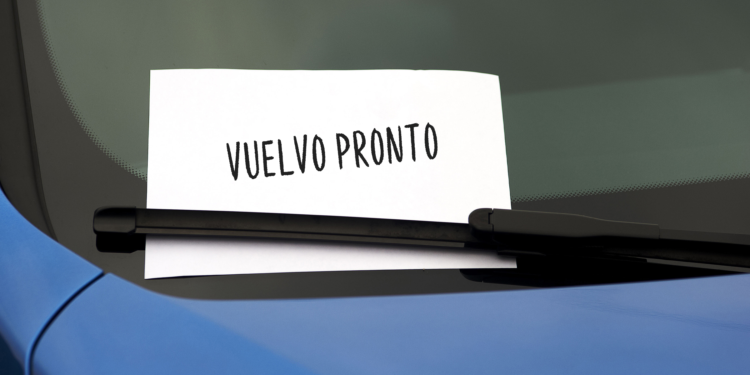 Una nota manuscrita escondida bajo el limpiaparabrisas de un automóvil | Fuente: Shutterstock