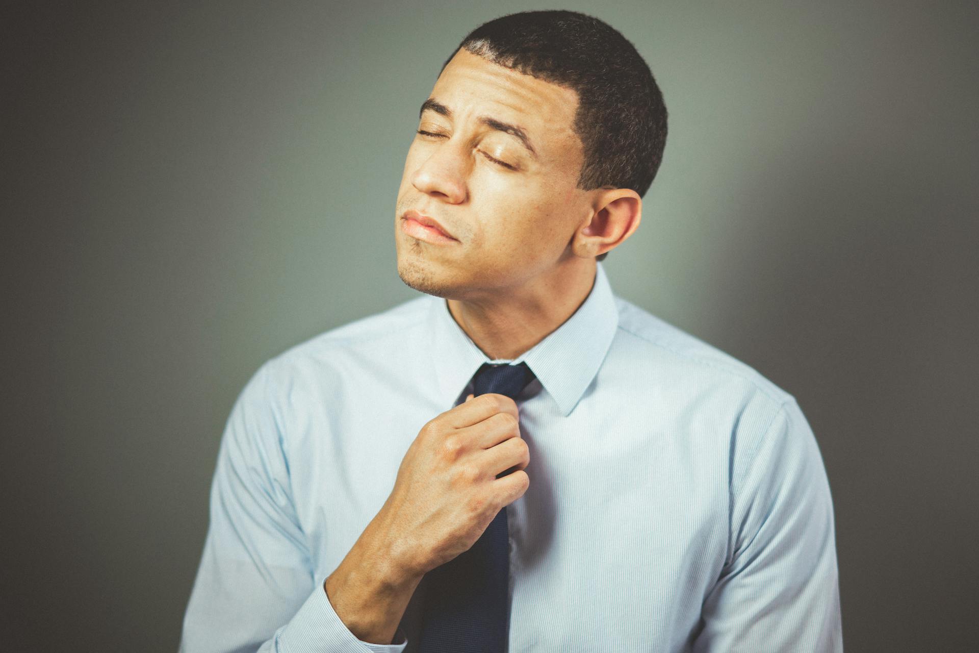 Un hombre infeliz sujetando su corbata | Fuente: Pexels