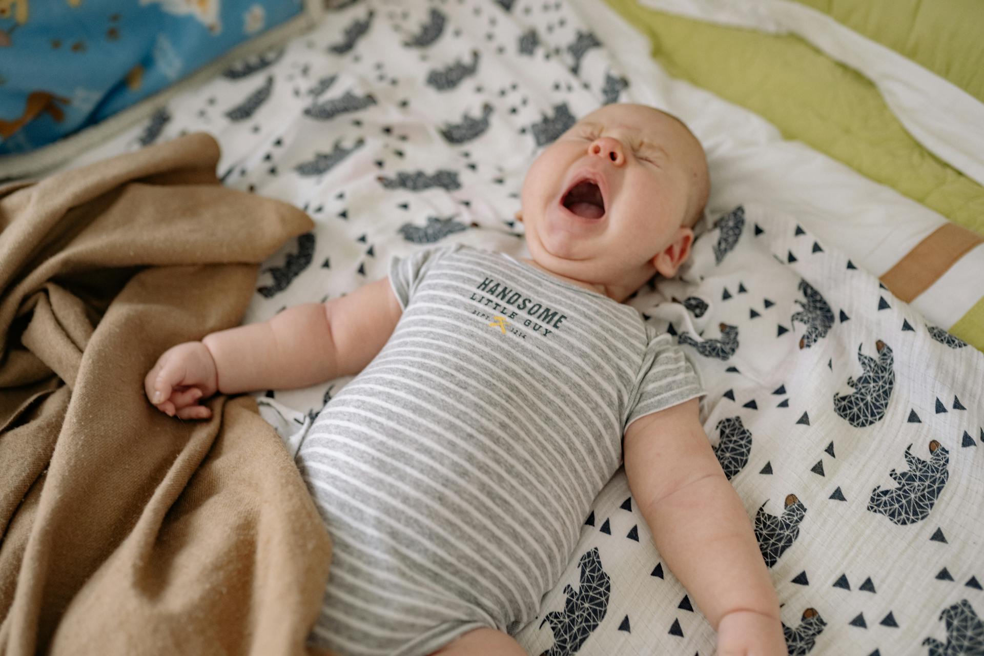 Un bebé llorando tumbado en la cama | Fuente: Pexels