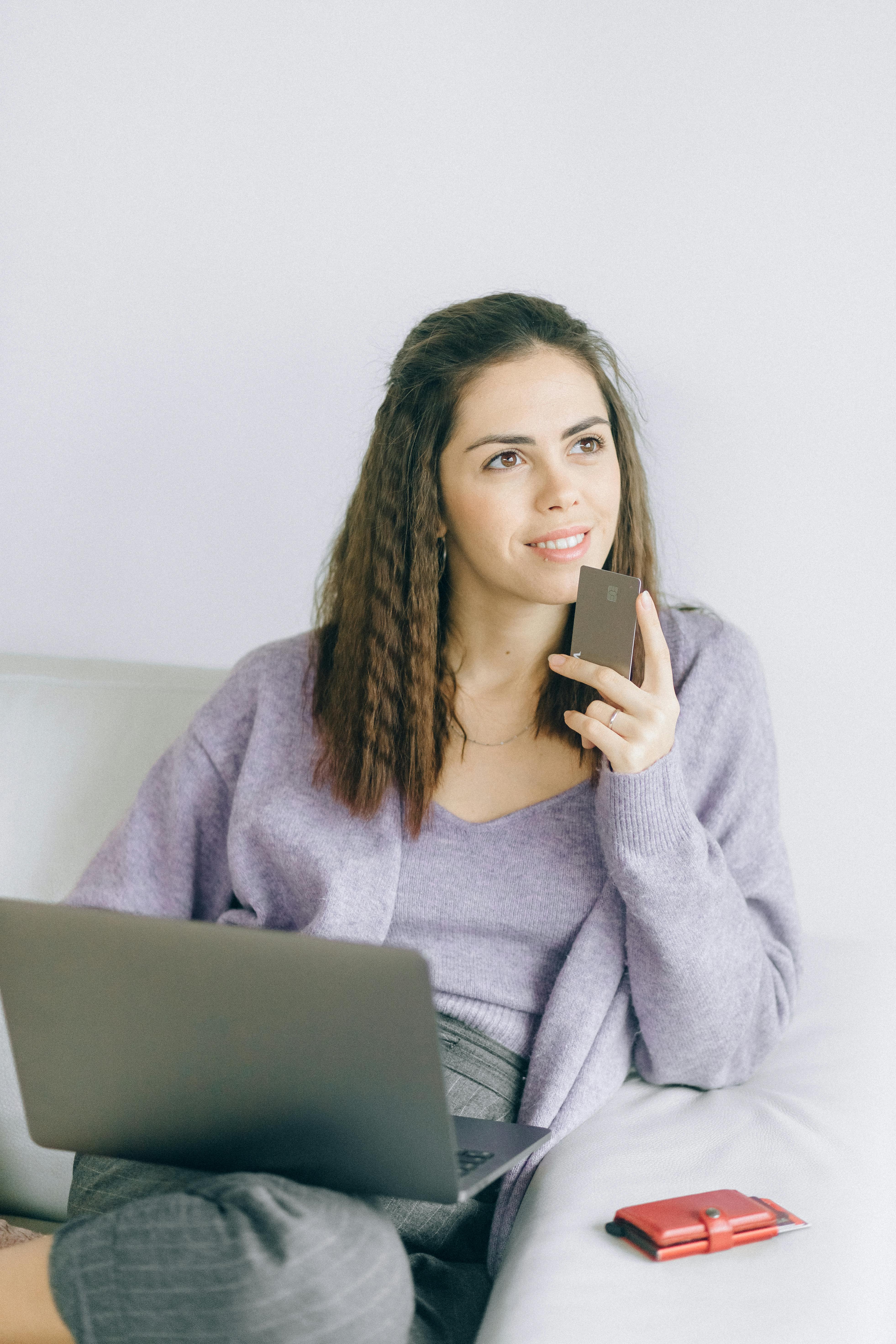 Una mujer con una tarjeta bancaria y un ordenador portátil | Fuente: Pexels