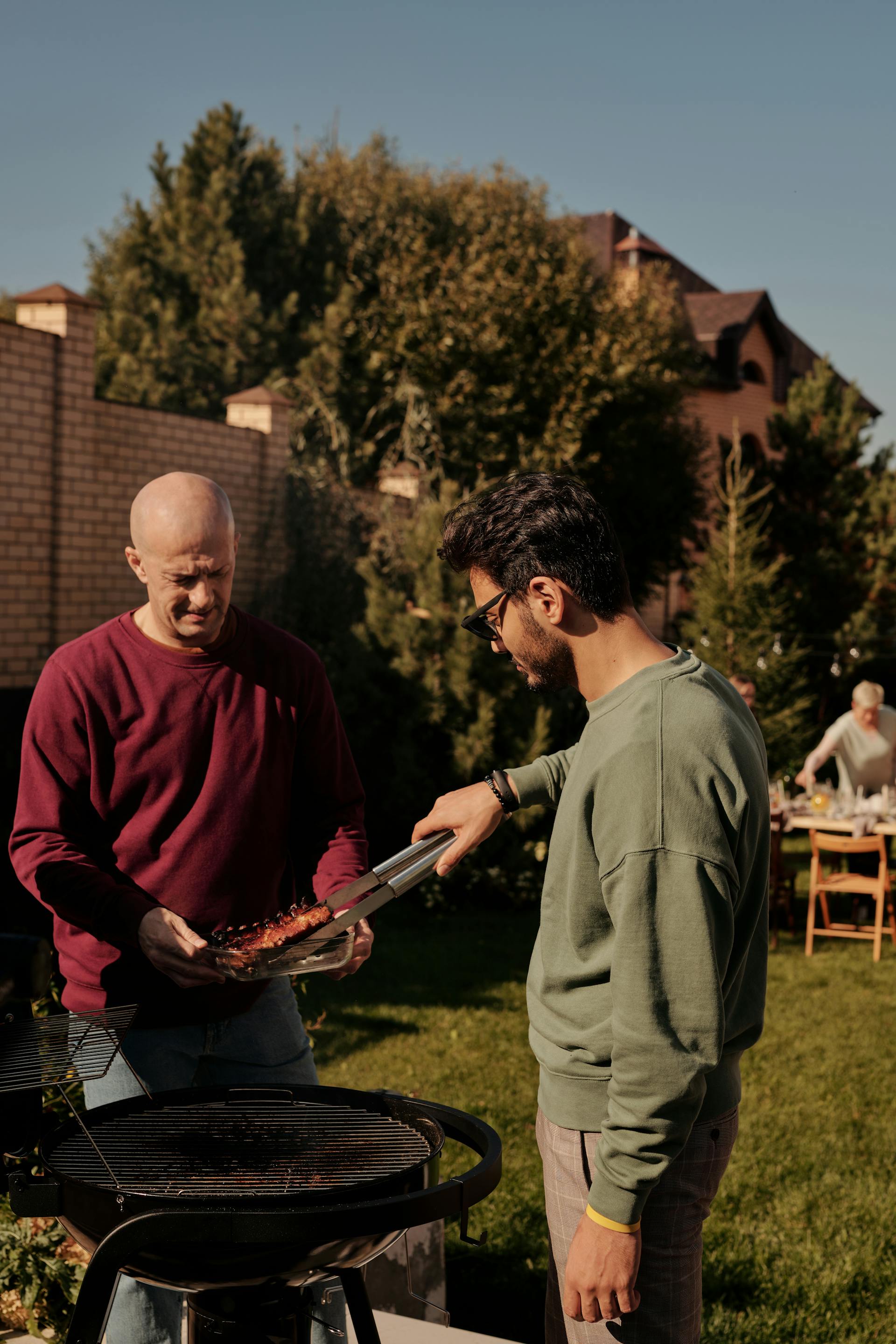 Dos hombres haciendo una barbacoa en el patio | Fuente: Pexels