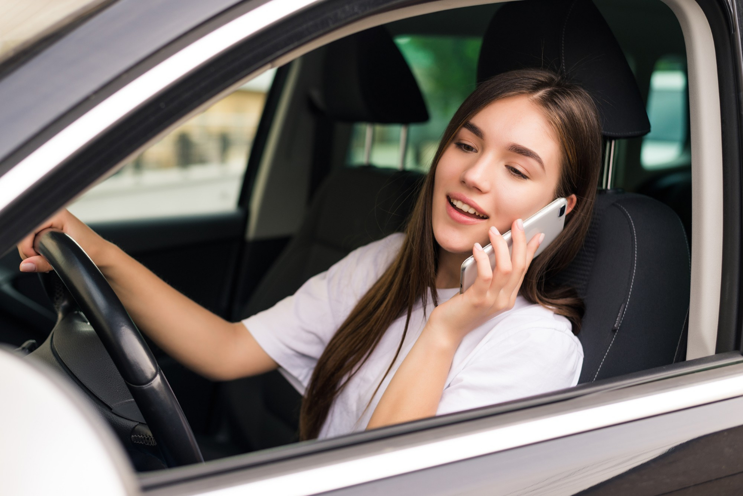 Una mujer encantada sentada en su automóvil y hablando por teléfono | Fuente: Freepik