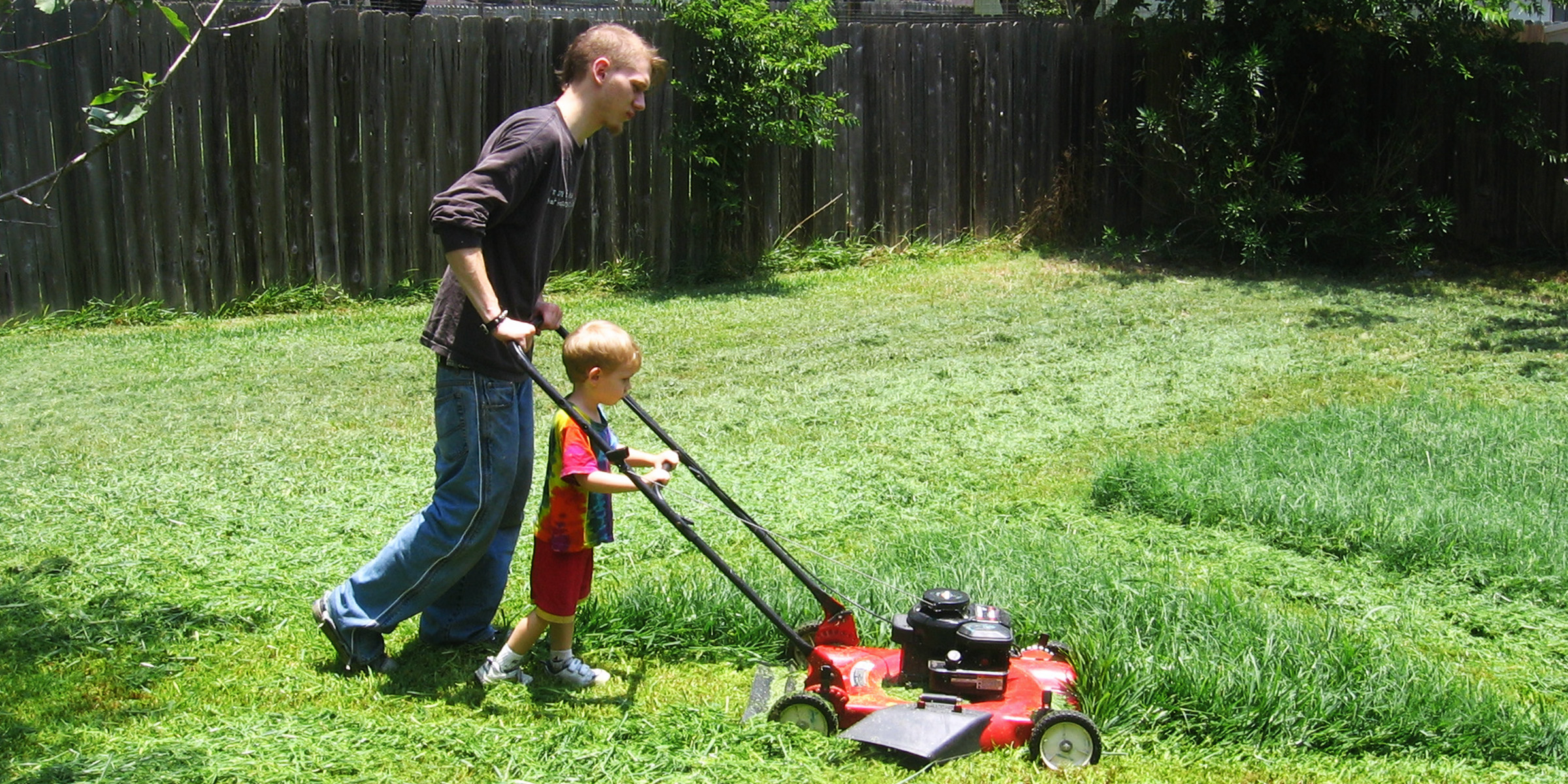 Un hombre y su hijo cortando el césped | Fuente: Flickr